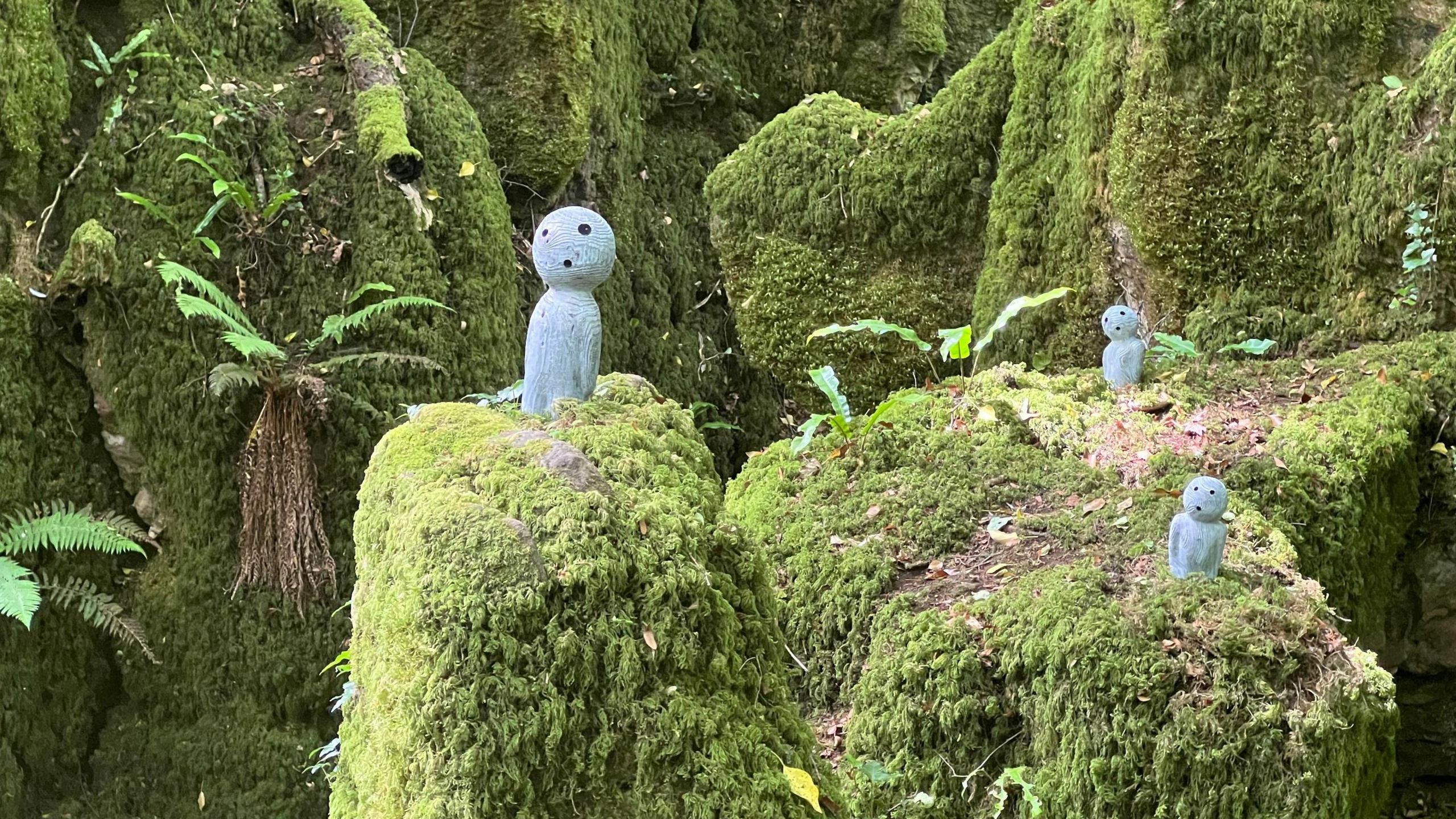 Small people-shaped sculptures among the mossy stones in Puzzlewood