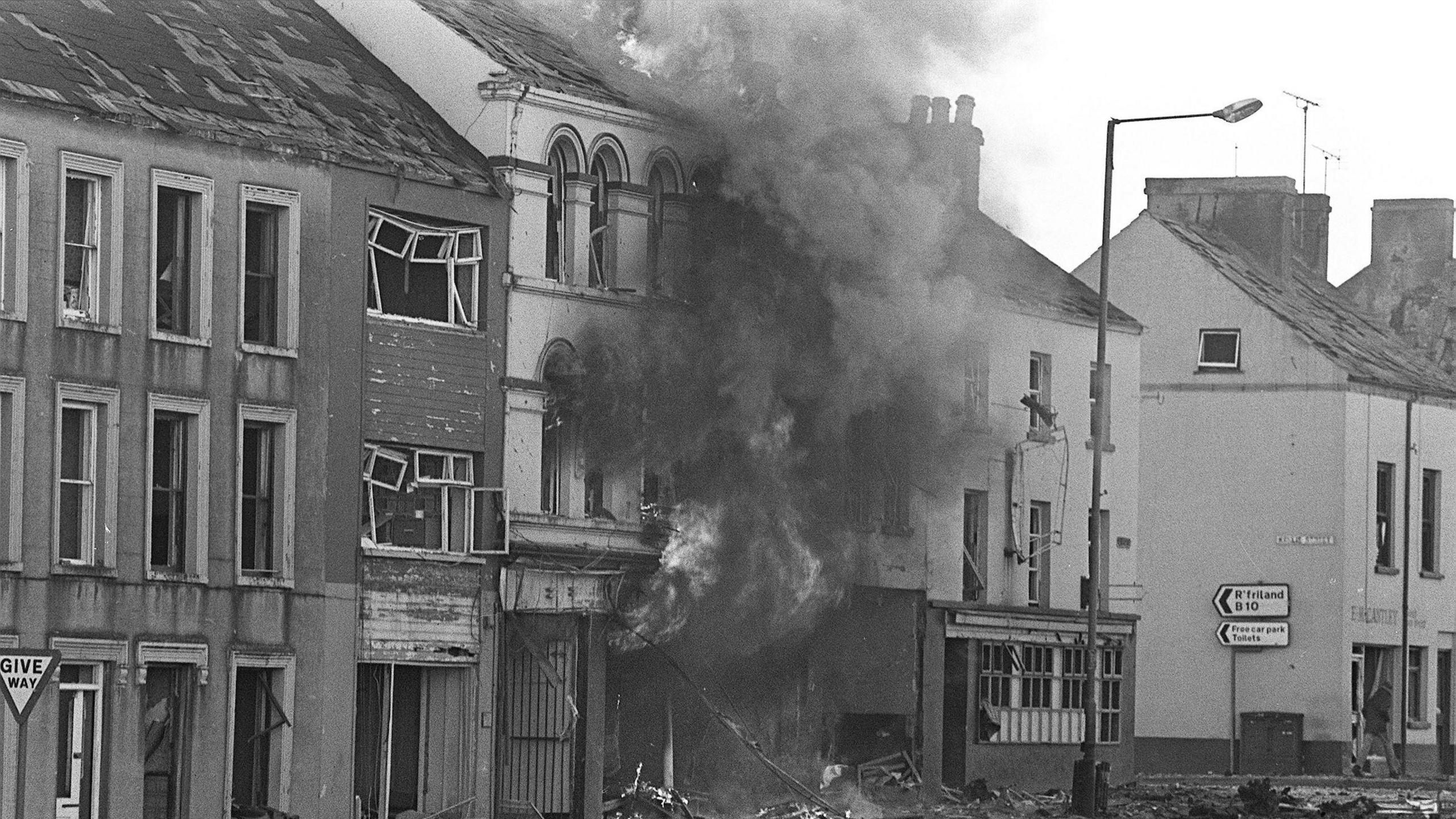 A black and white archive photo showing smoke coming from a bomb-damaged building in Banbridge after the County Down town was badly damaged by a car bomb in 1980 