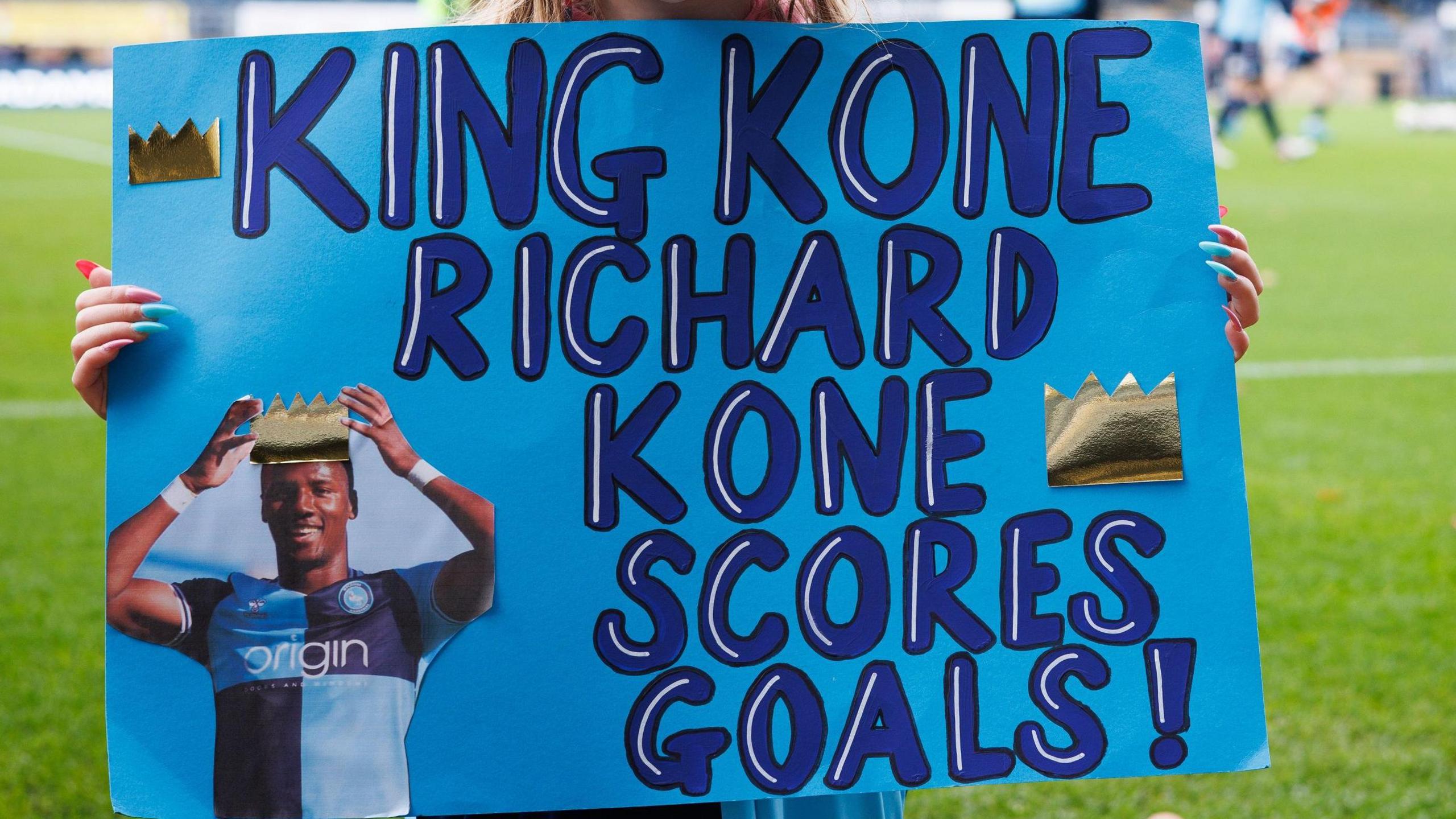 A young Wycombe Wanderers supporter holds up a sign abour her favourite player, Richard Kone