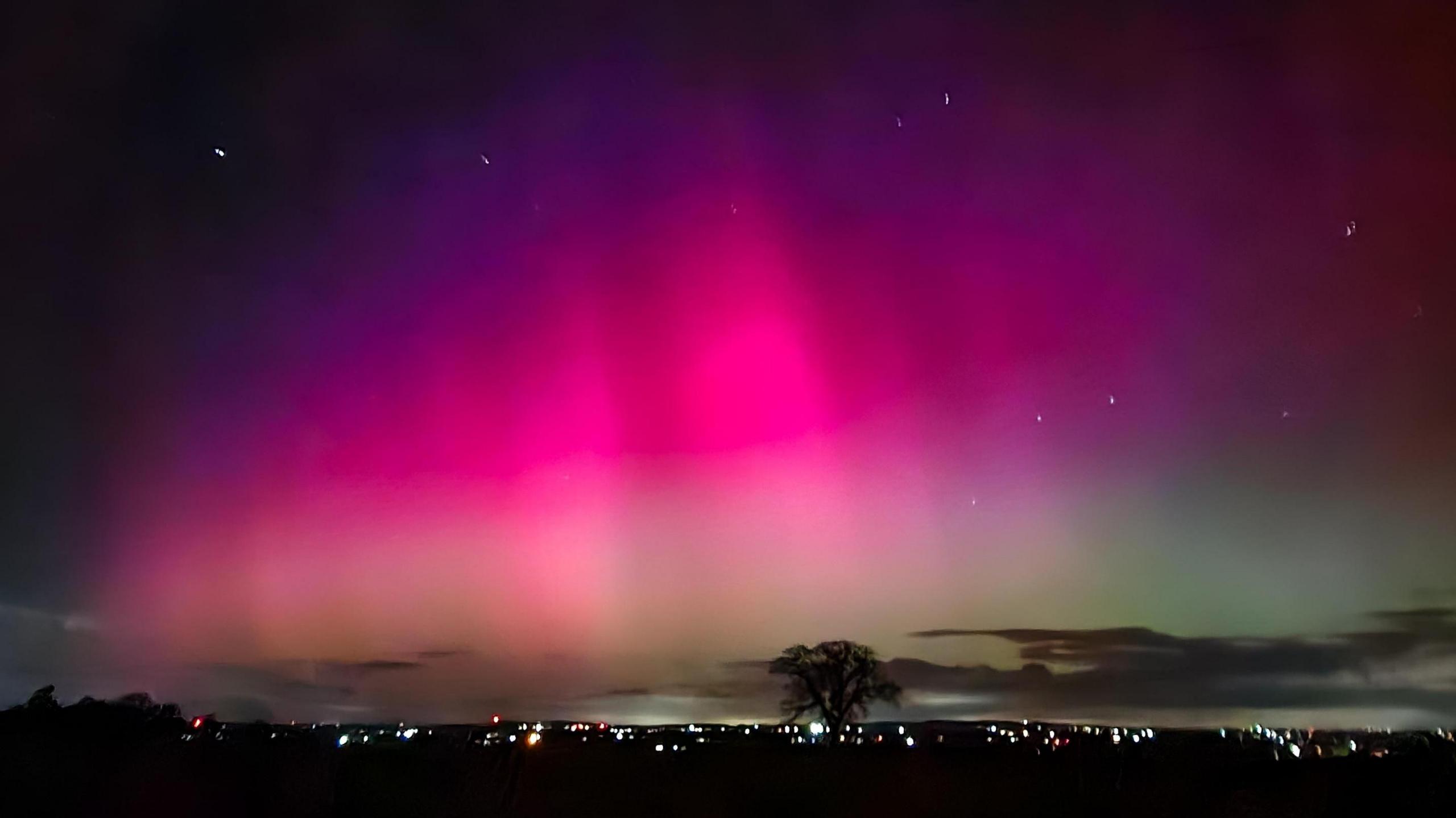 An evening sky with purple and pink hues and stars across a city skyline 