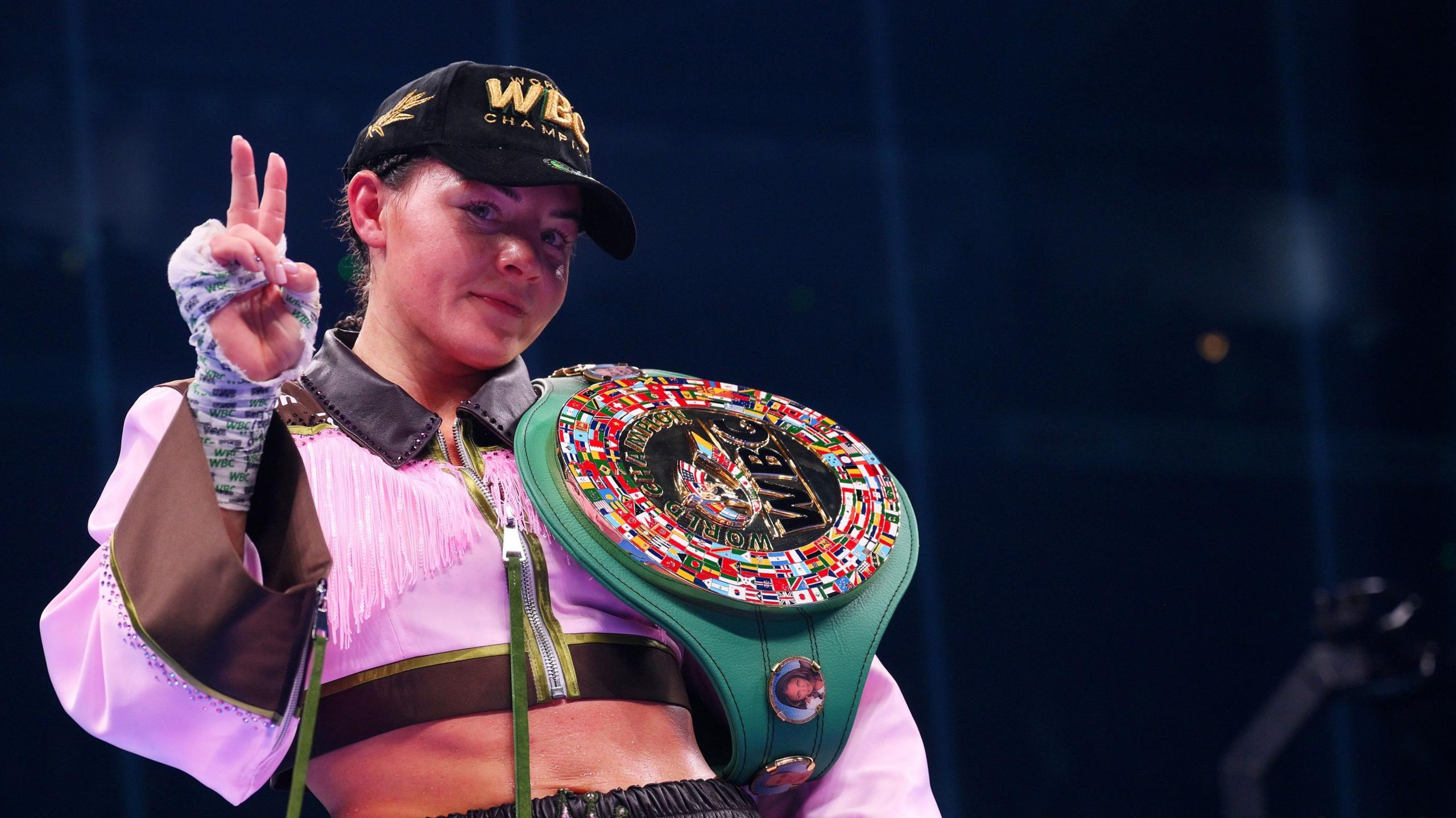 Sandy Ryan with her WBC belt hung over her shoulder with two fingers up to indicated that she had just become a two-weight world champion