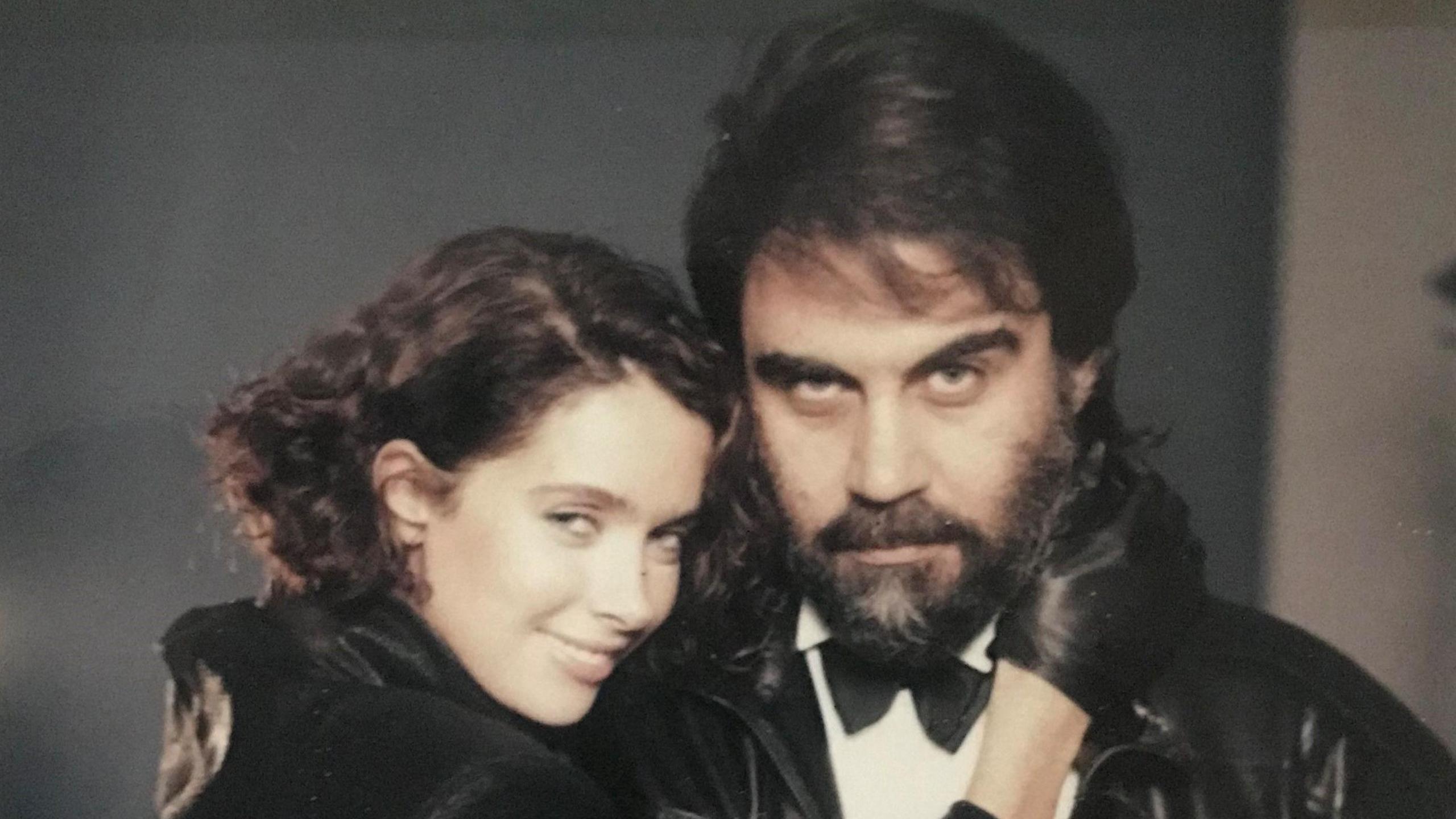 Kathy Hill, wearing a black top, poses with Vangelis, who is wearing a black bow tie and tuxedo 