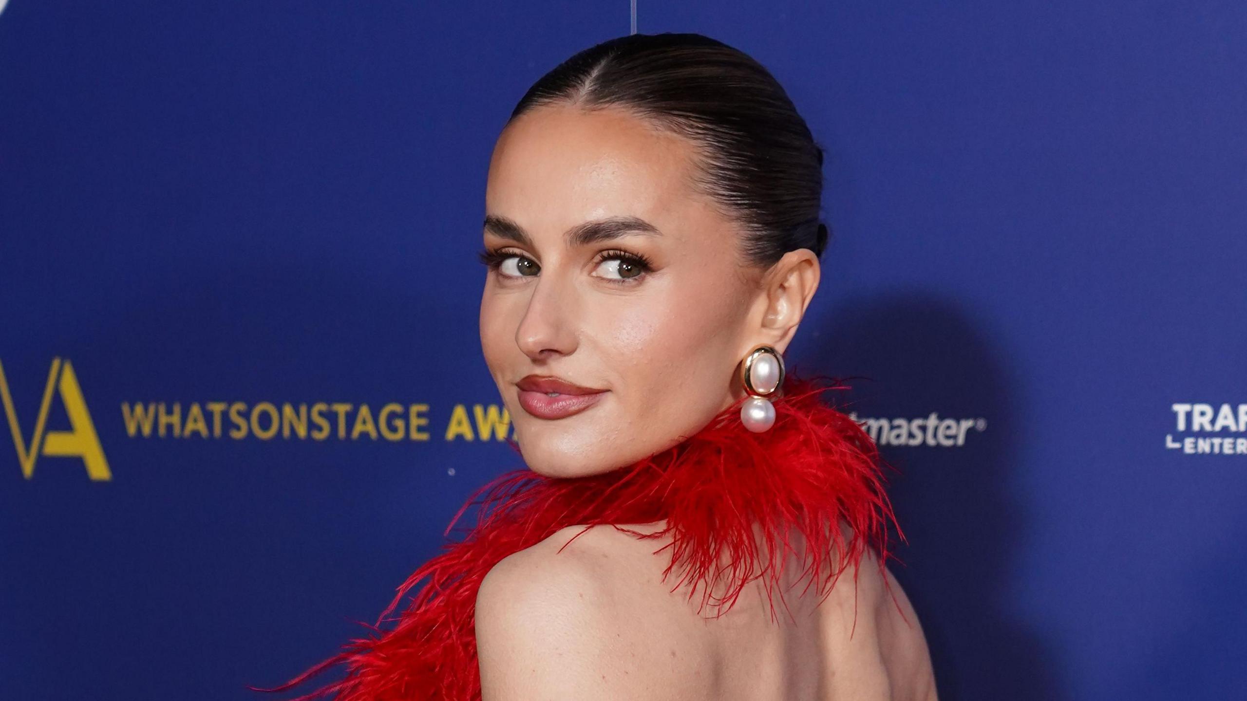 Amber Davies at the WhatsOnStage Awards wearing red feathered halterneck dress 