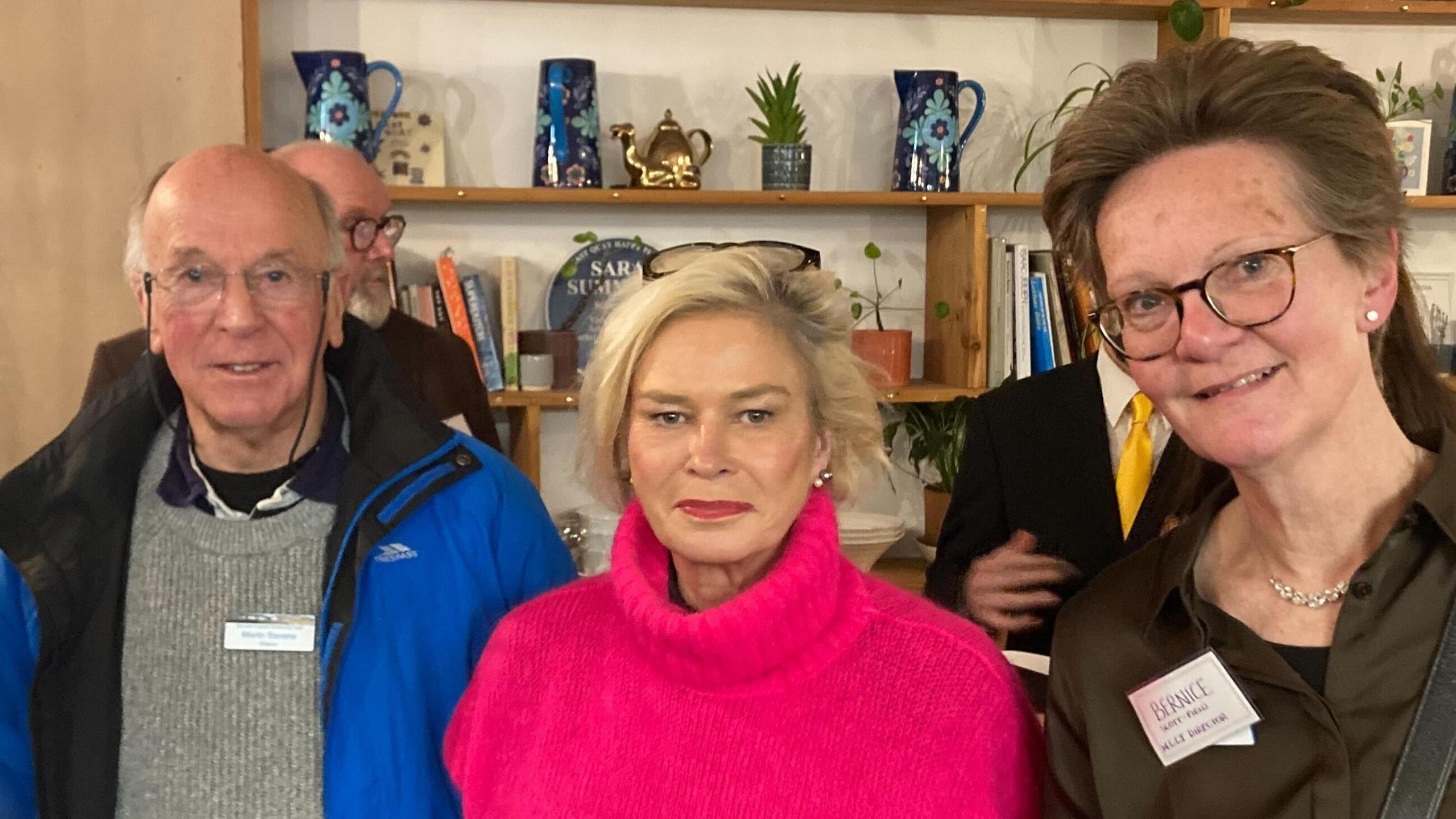 A man in a blue coat is stood next to two women. One woman, Tiverton and Minehead MP Rachel Gilmour, has a pink jumper, the other woman is wearing a brown shirt.