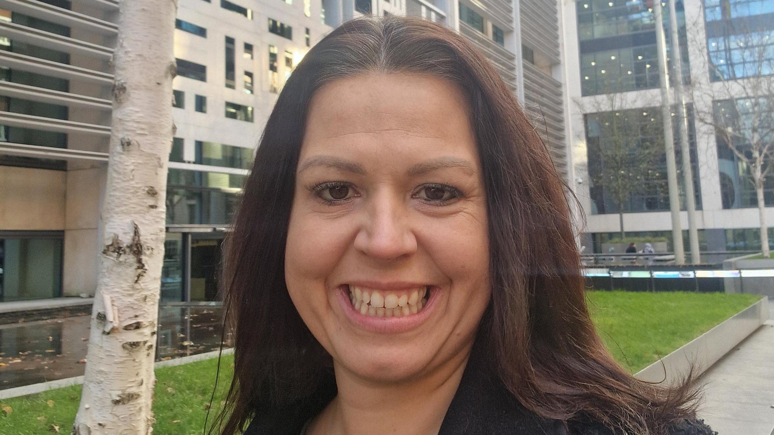 Katie Kendrick has shoulder-length brown hair and is smiling to the camera