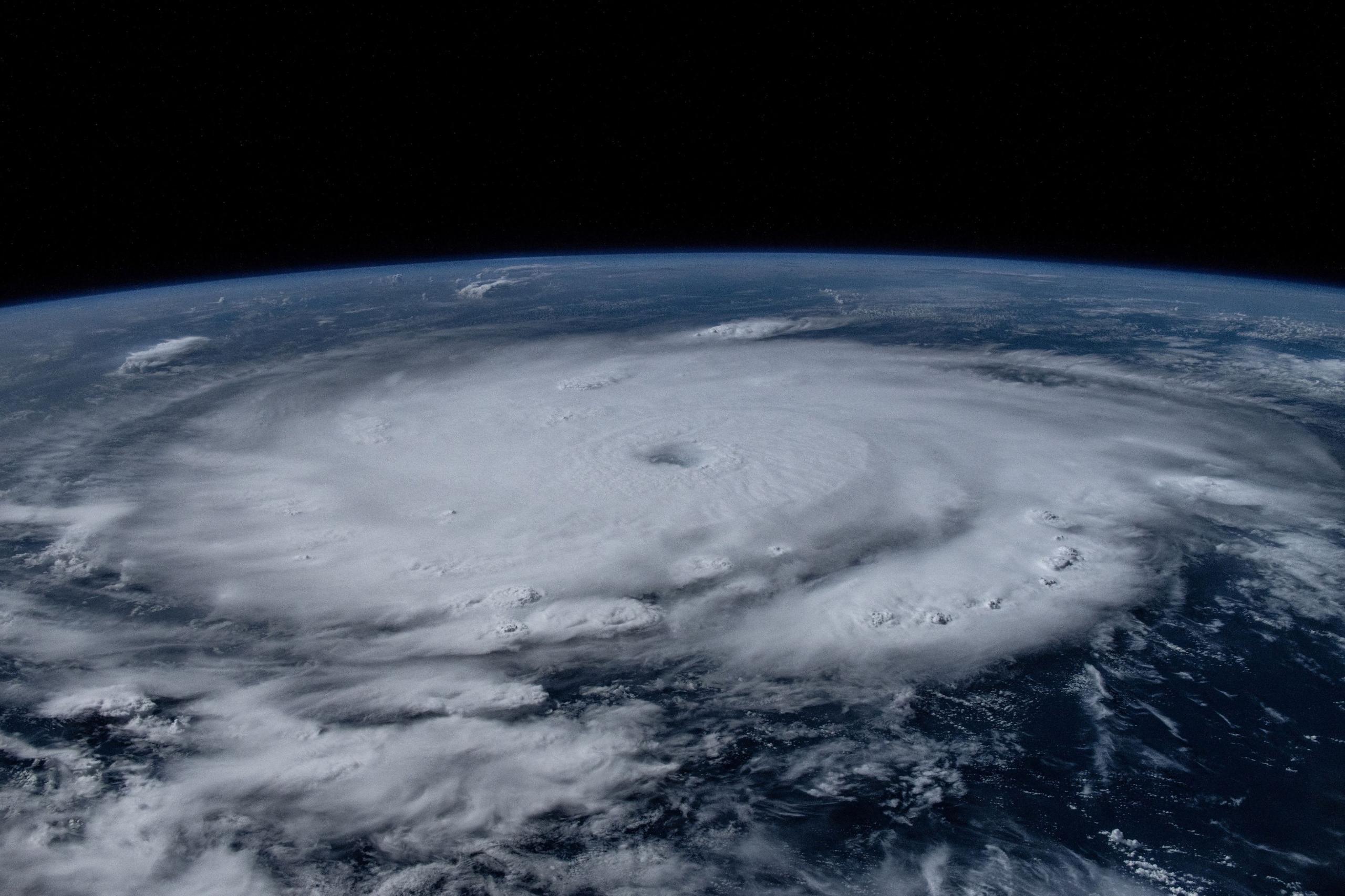 The view of the hurricane from space shows swirling white clouds across the curvature of the earth