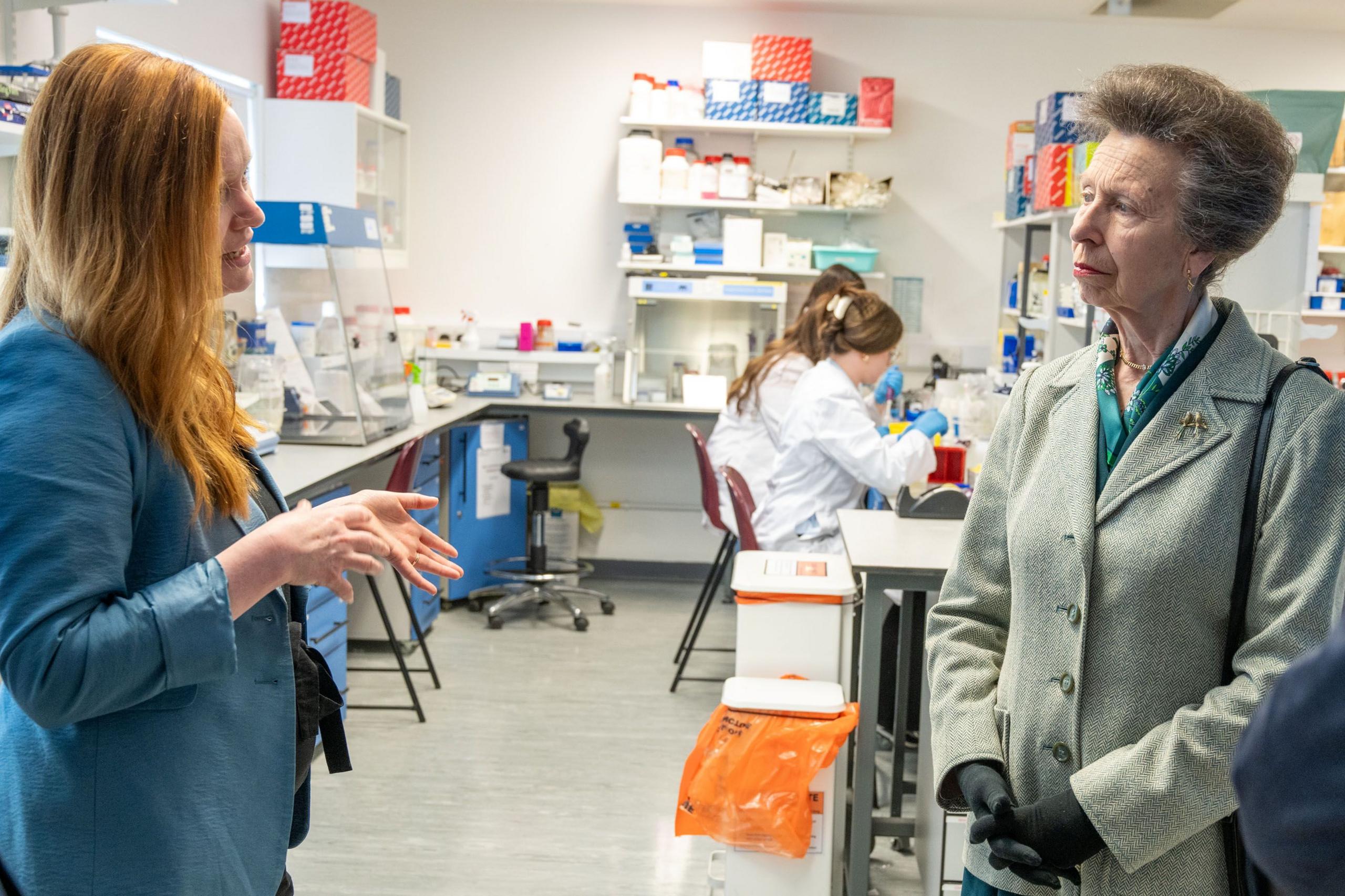 Tow ladies stand facing each other in a research lab