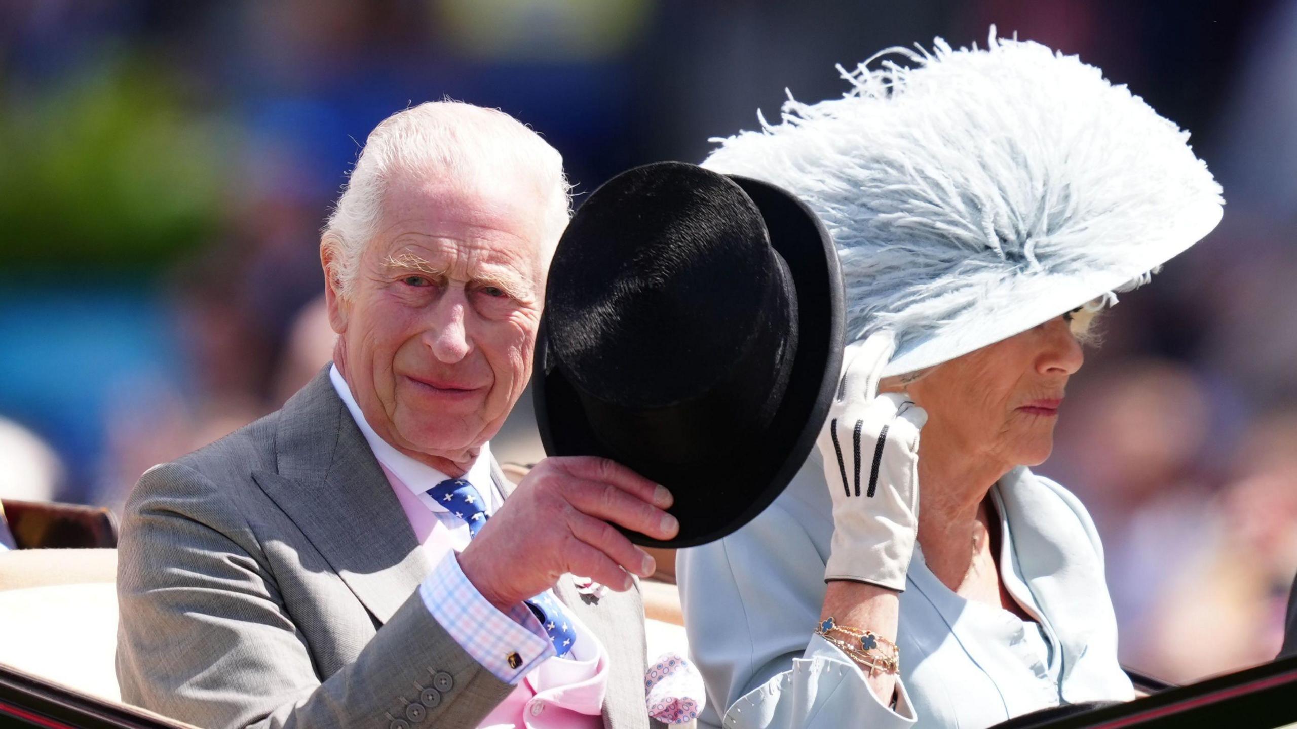 King Charles III and Queen Camilla waving from an open top carriage