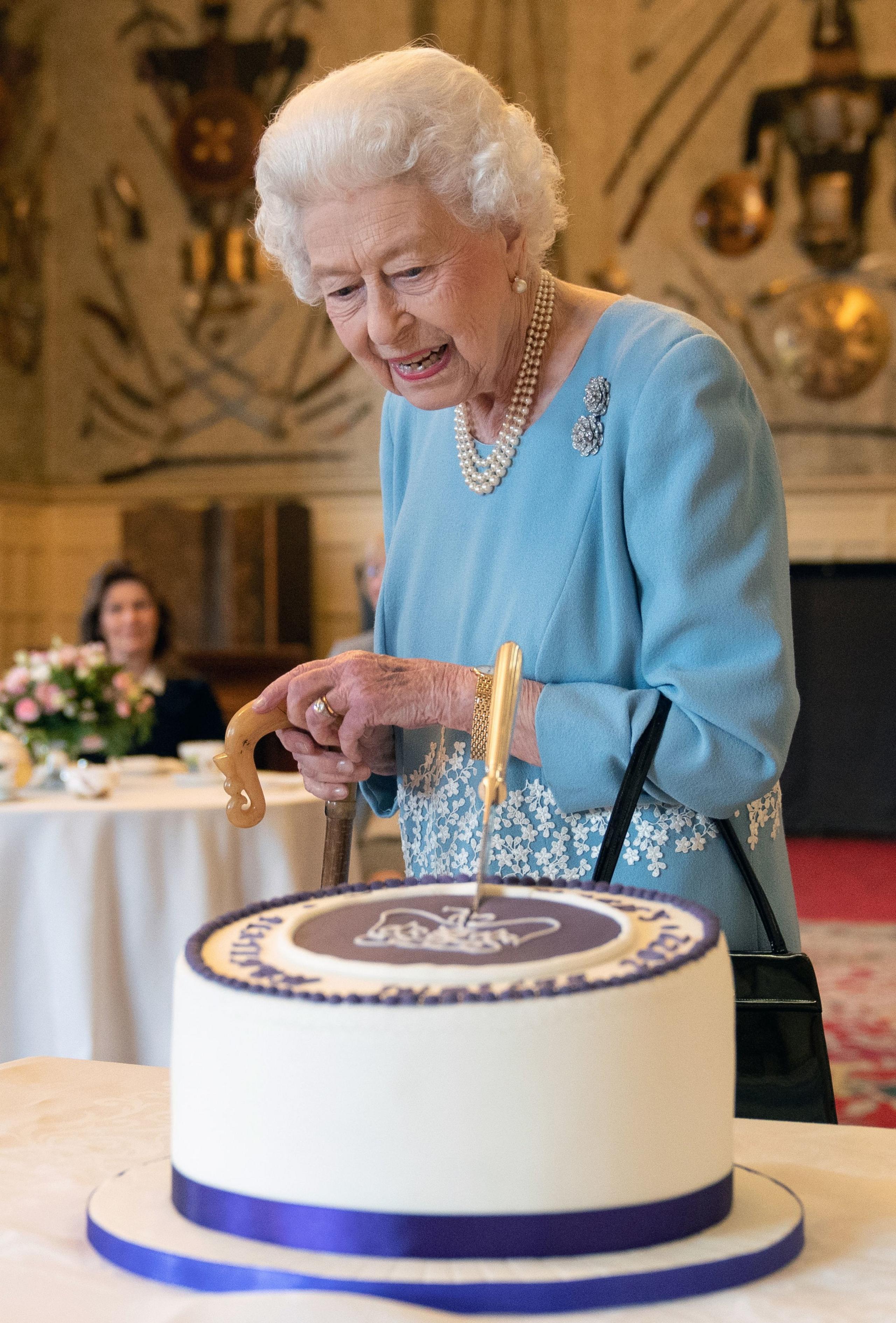 The Queen cuts a cake to celebrate the start of the Platinum Jubilee during a reception in the Ballroom of Sandringham House on 5 February