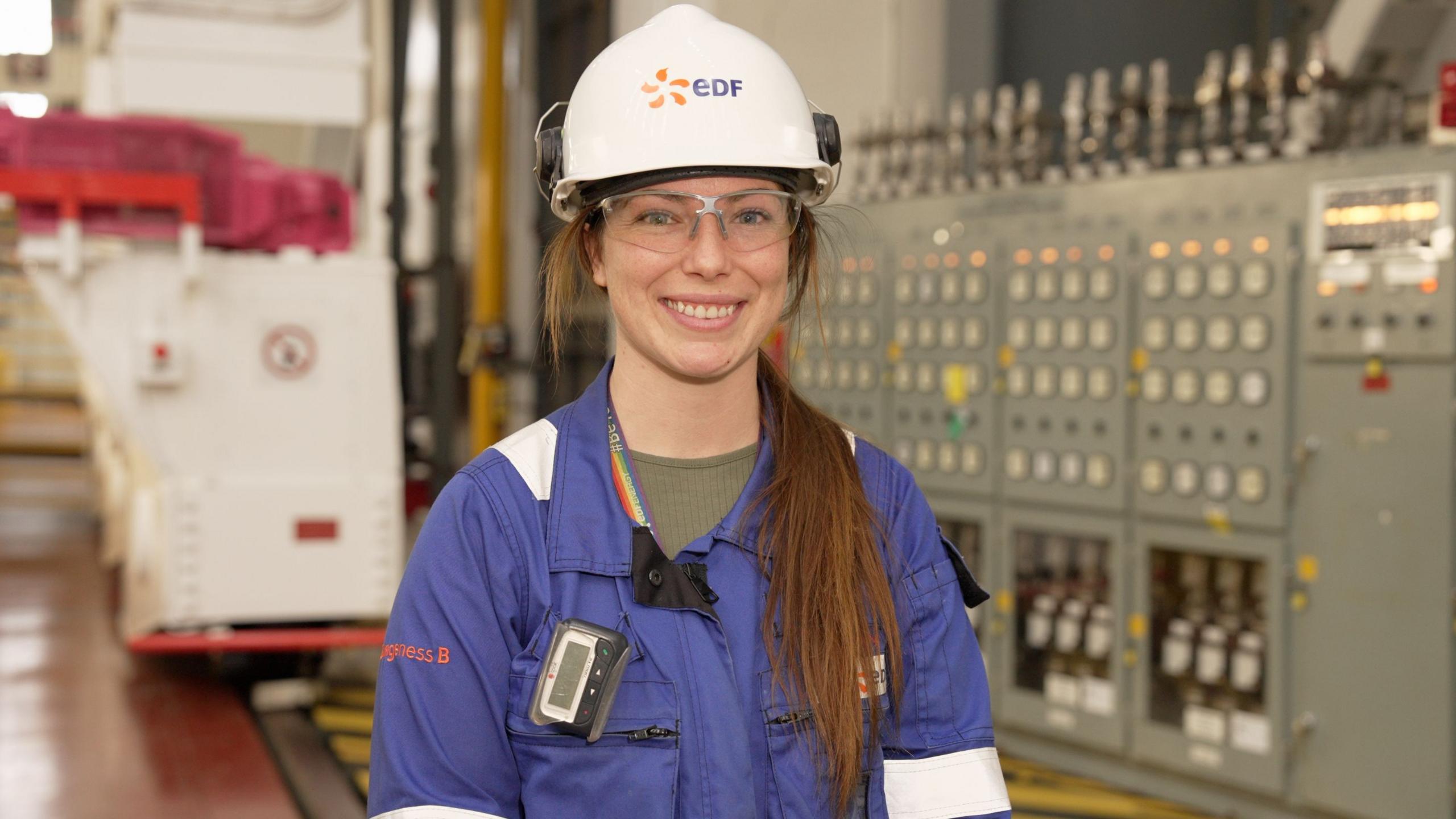 Chloe Tilly - a woman in a blue work suit with a white hard hat.