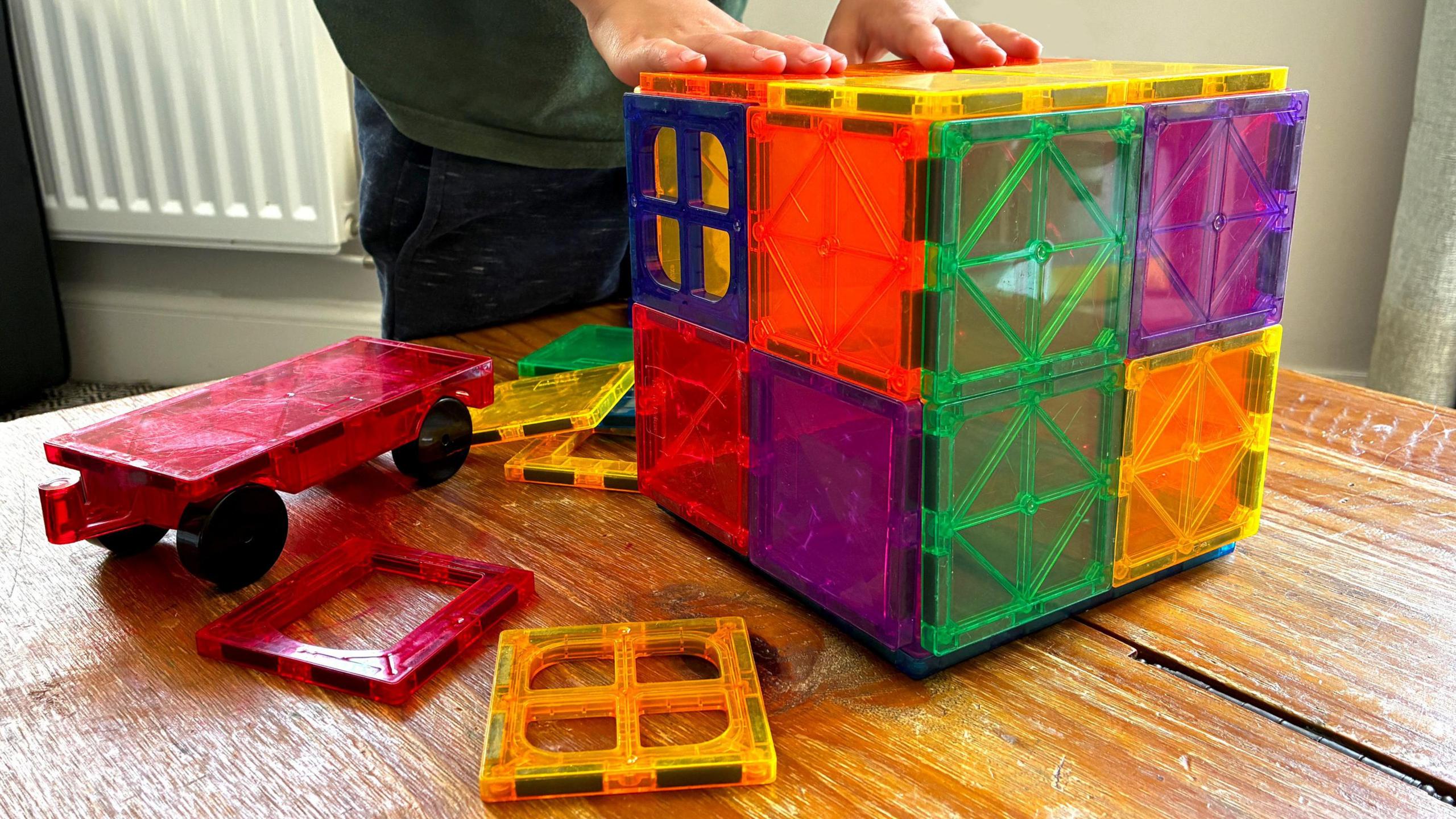 a child's hands playing with a multi-coloured toy box made with magnets
