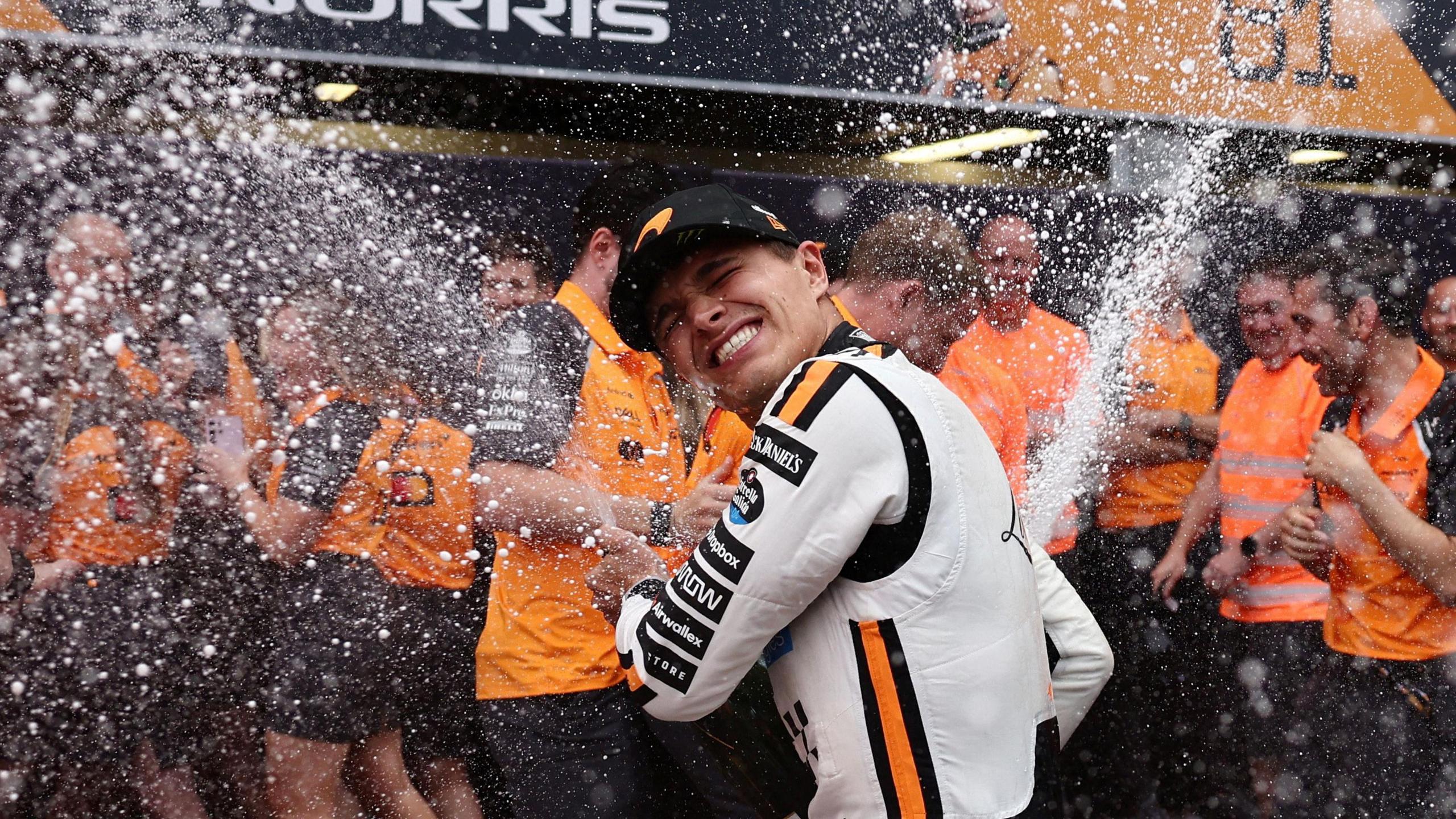 Lando Norris celebrating with champagne with his team