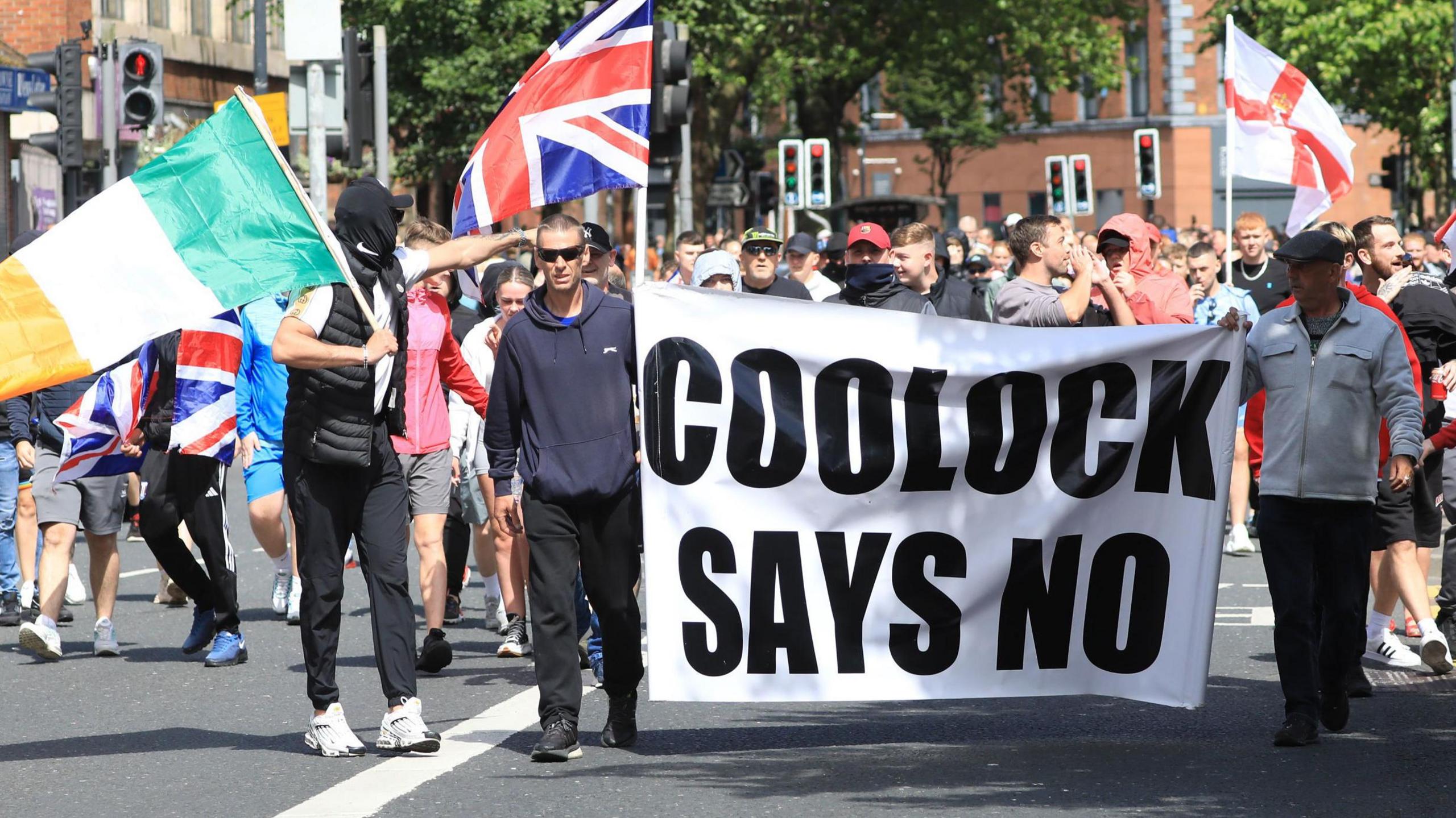 Protesters carrying a banner which says "Coolock says no". Others are carrying flags. 