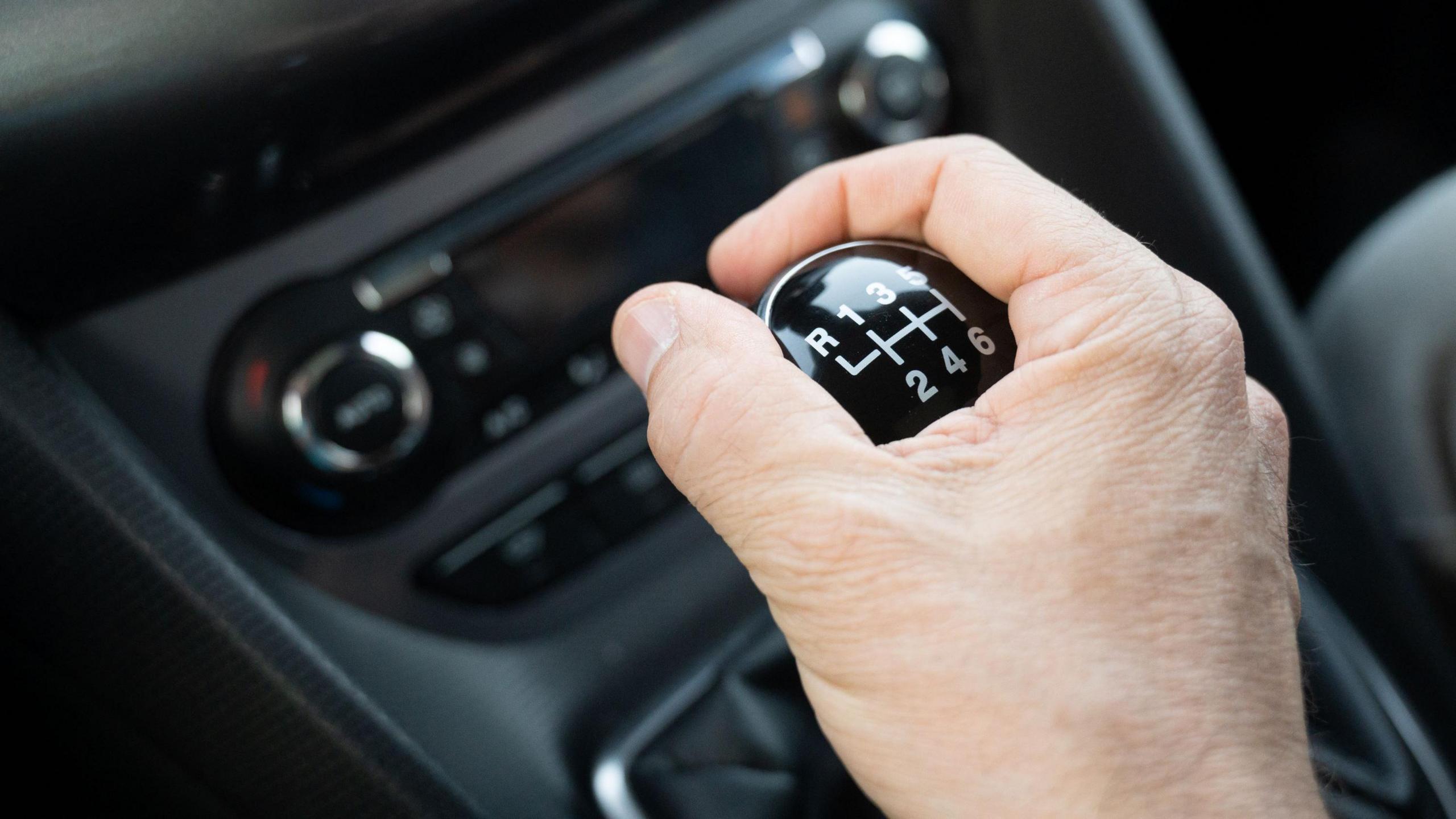 A hand on a gear stick in a car.