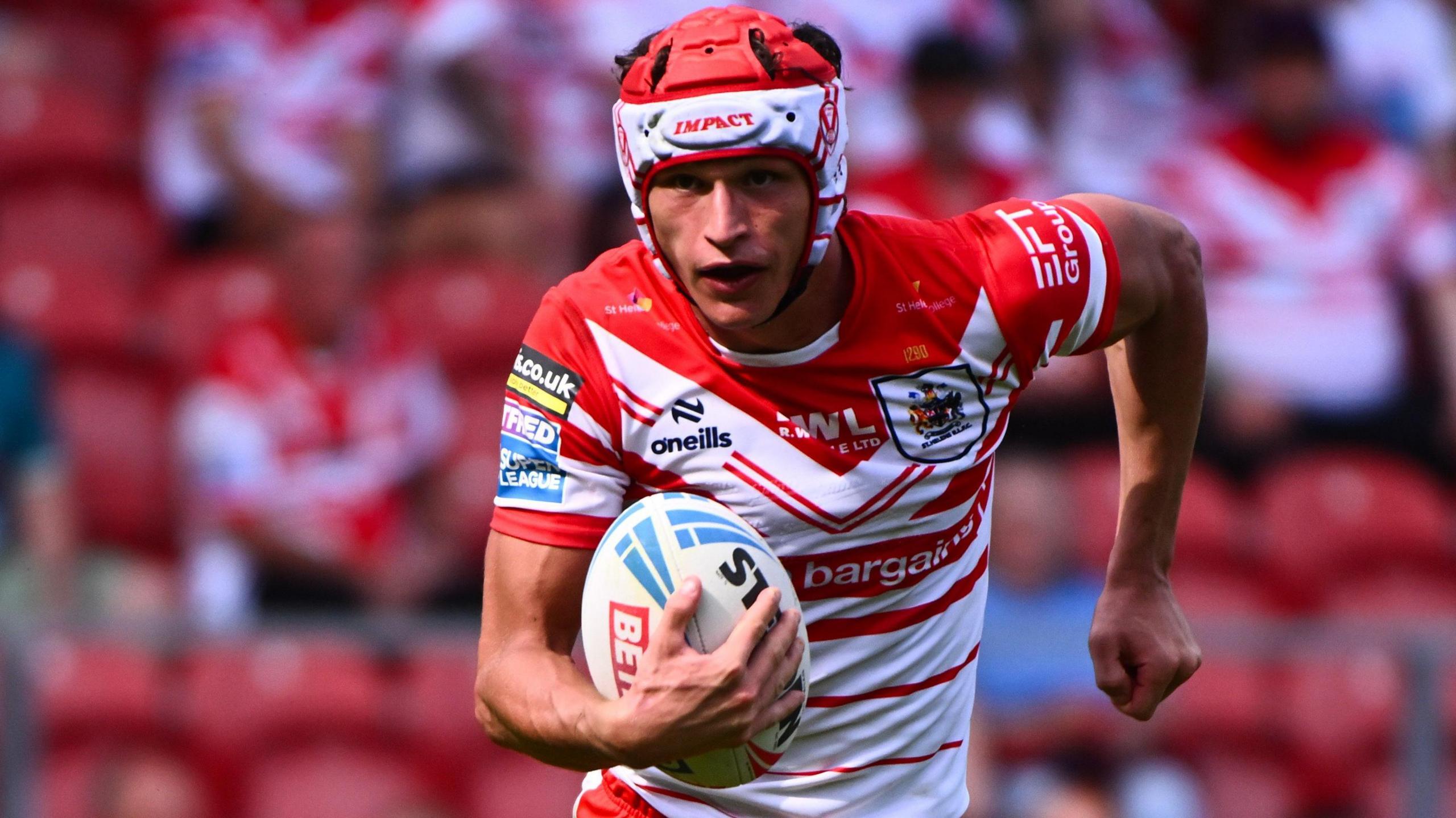 Harry Robertson, wearing St Helens' red and white jersey, runs with a rugby league ball in his right hand