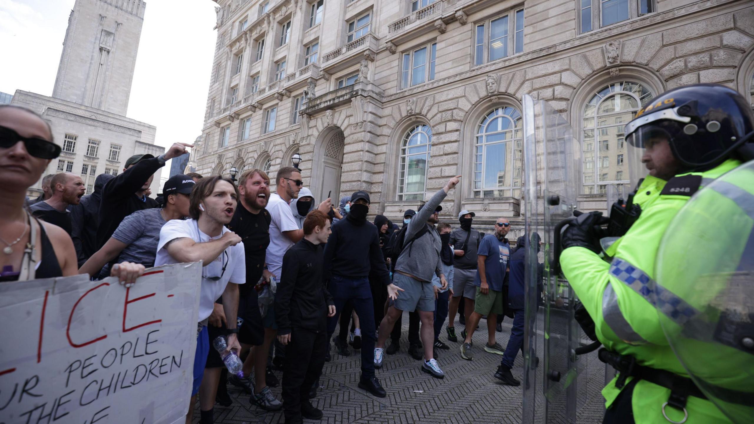 Police officers face protesters in Liverpool