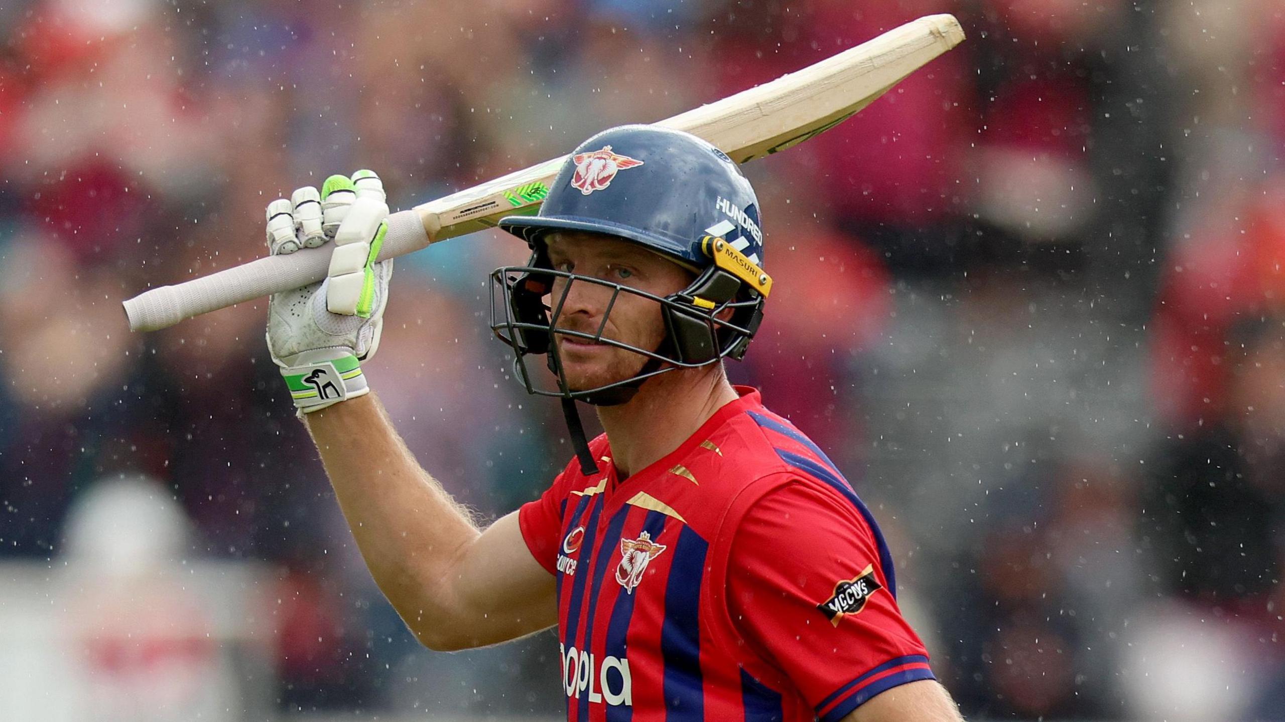 Jos Buttler wearing a helmet and raising his bat while playing for Manchester Super Giants