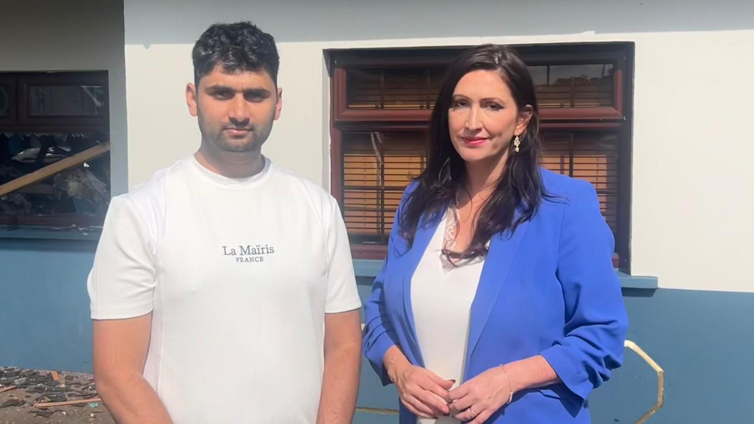 Abjan Acharya in a white tshirt and Emma Little-pengelly in a blue blazer and white top, outside fire damaged bar