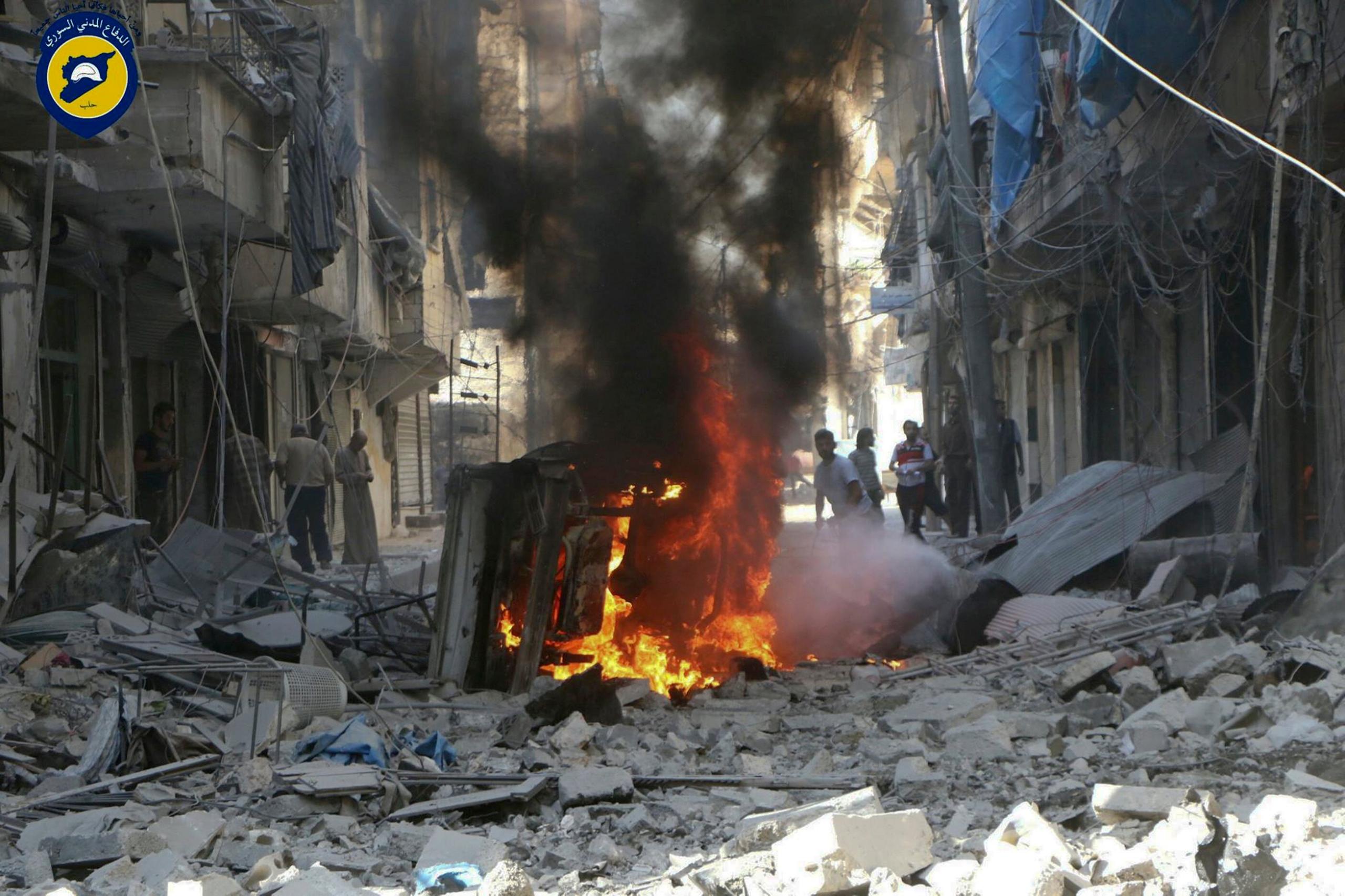 In this photo provided by the Syrian Civil Defense group known as the White Helmets, Syrians inspect damaged buildings after airstrikes by government helicopters on the rebel-held Aleppo neighborhood of Mashhad, Syria, Tuesday Sept. 27, 201