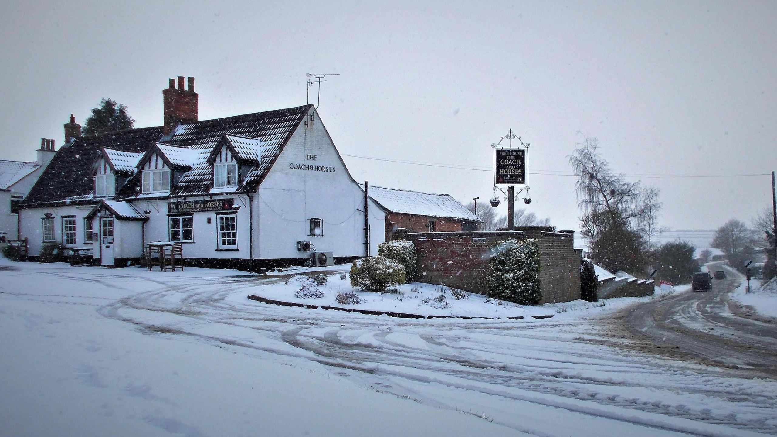 Snow on the road at Hemingby, near Horncastle, with a pub pictured in the background.