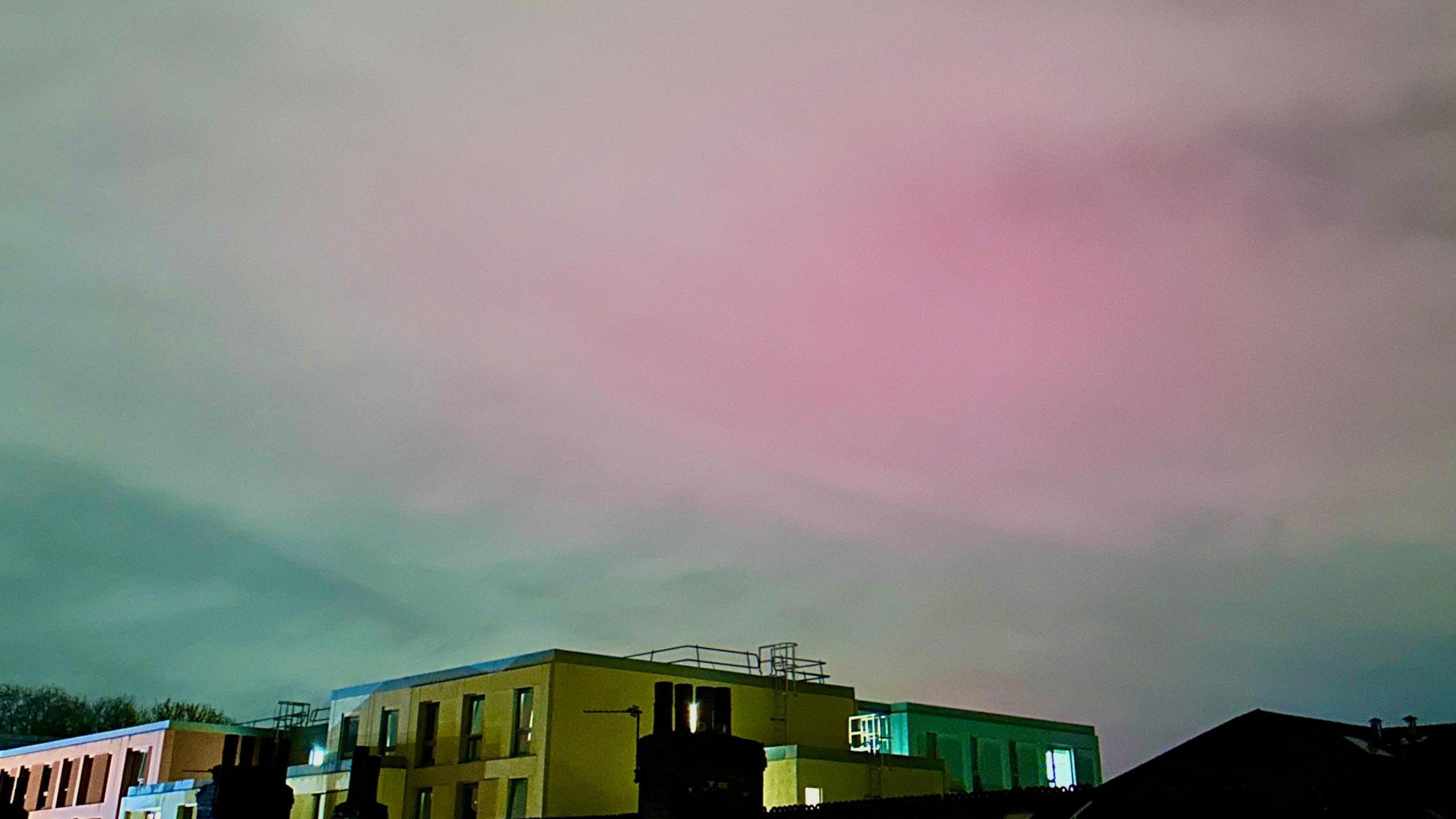 A faint pink glow through the clouds over houses in Manchester