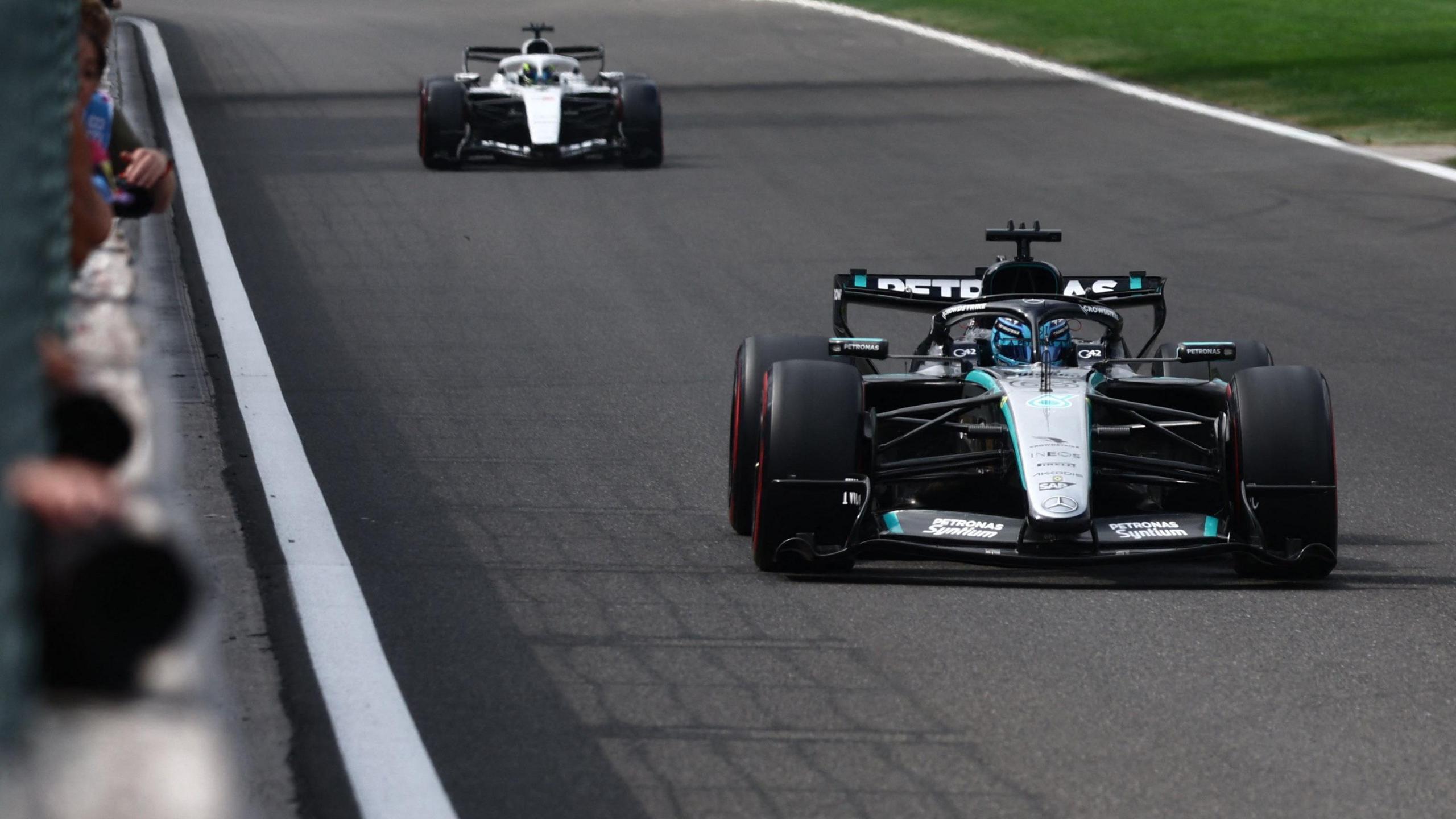 George Russell driving the Mercedes during Belgian Grand Prix qualifying with a Cadillac in the background