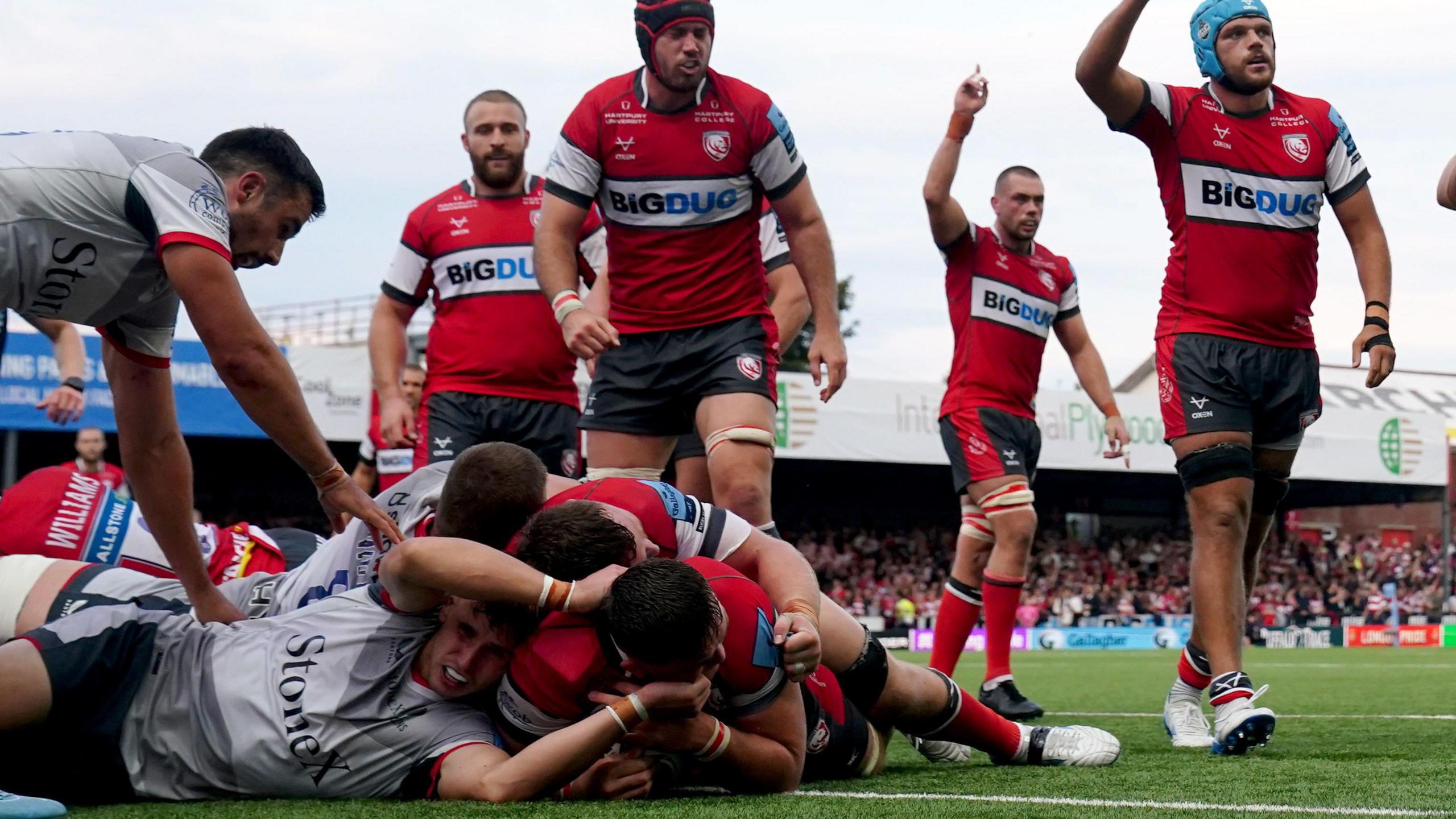 Gloucester's Freddie Thomas scores a try against Saracens at Kingsholm. He is underneath a pile of bodies while other Gloucester players celebrate in the background