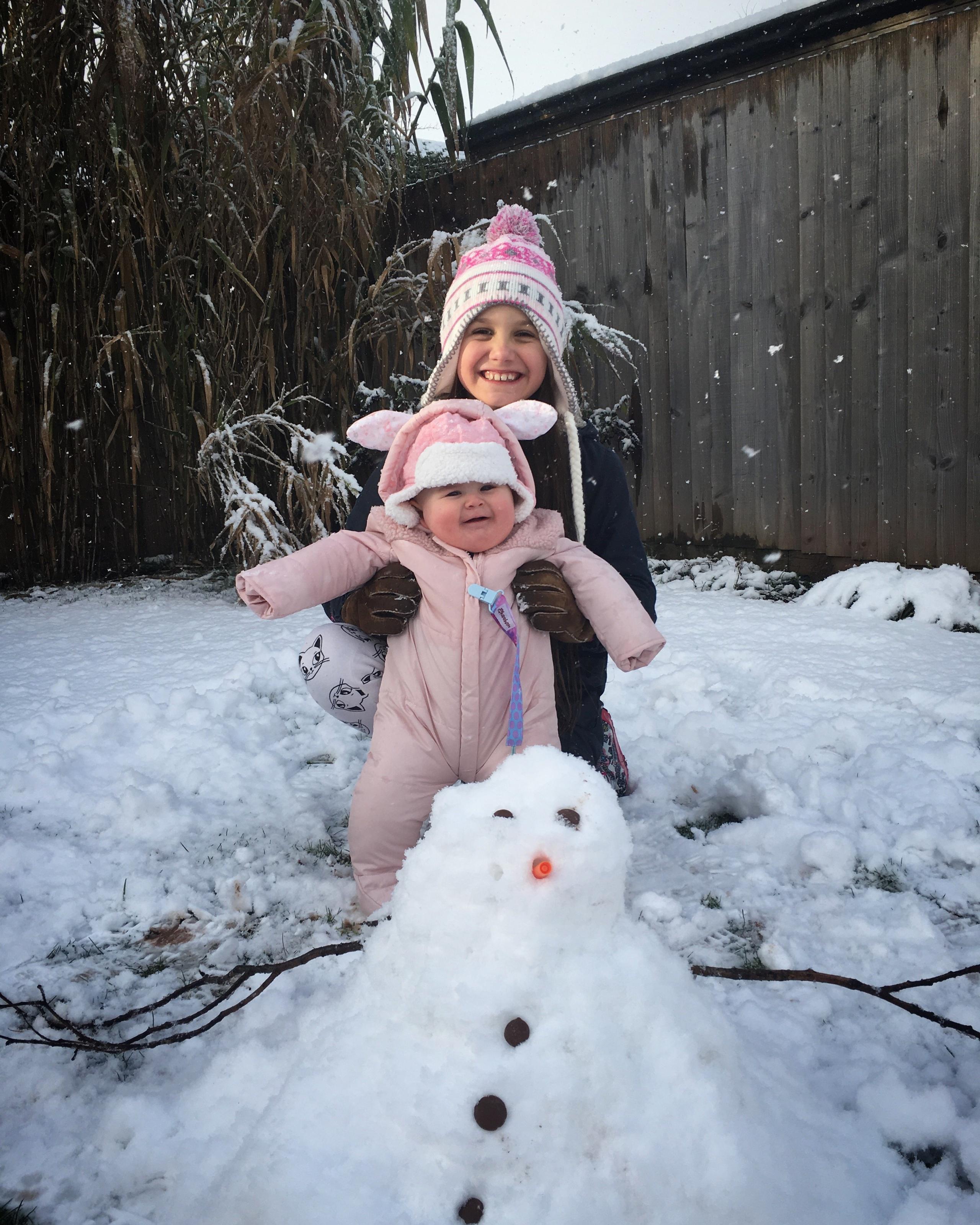 A girl and her baby sister in the snow