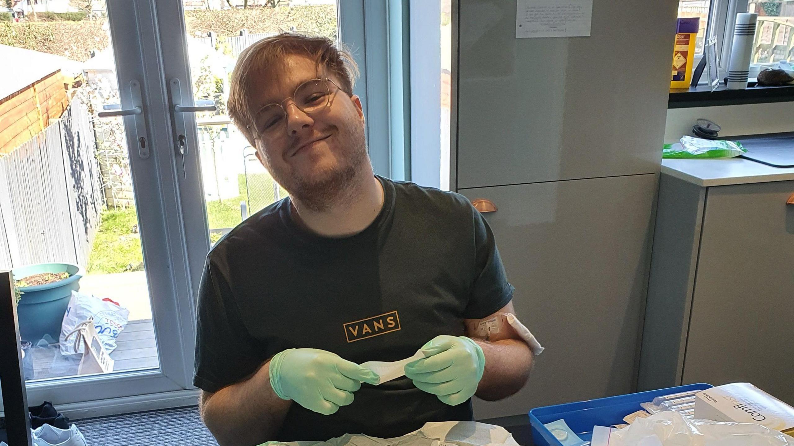 Young man with glasses sits at table with PPE 