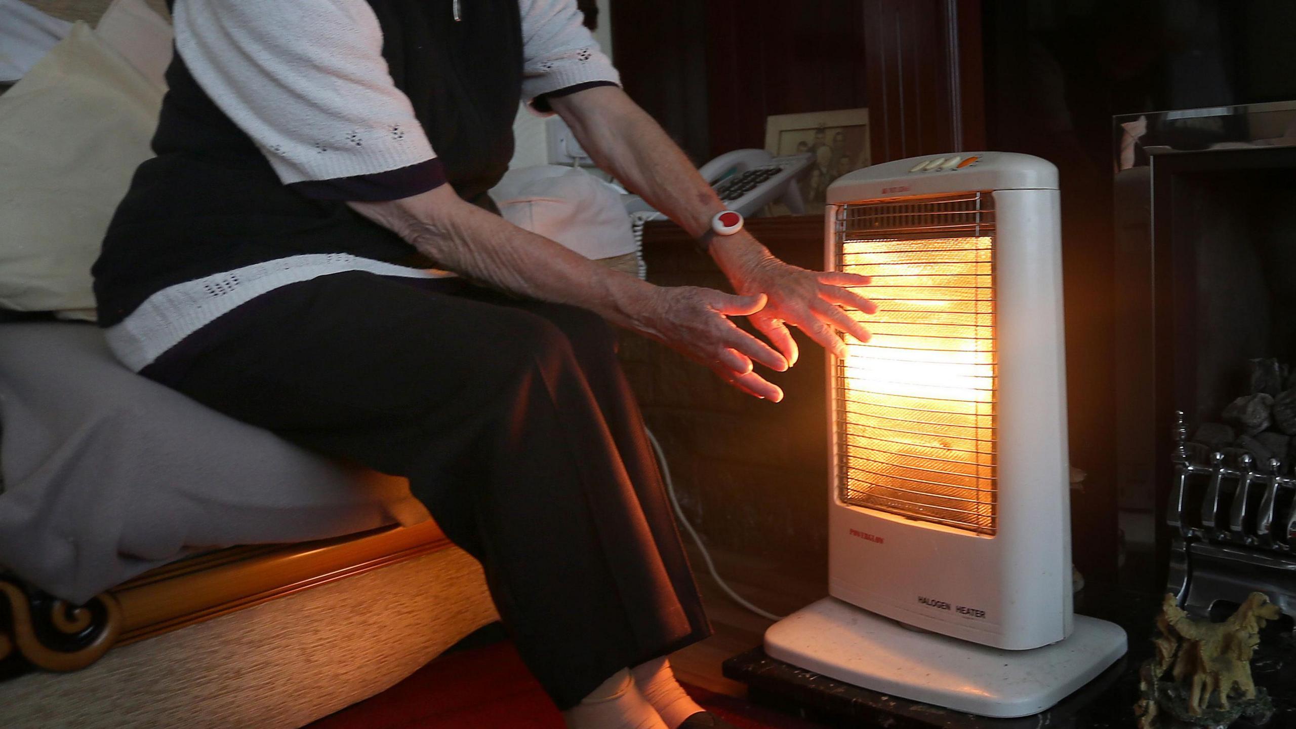 Elderly woman with heater