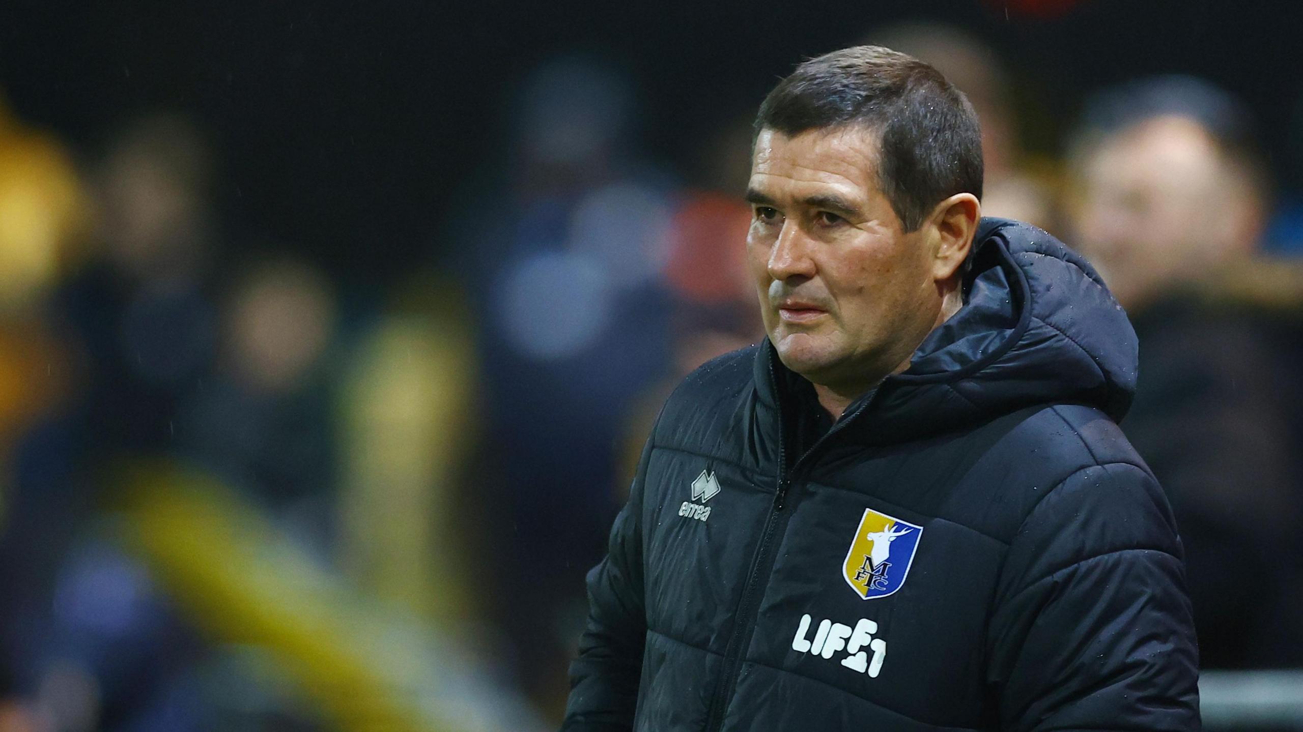 Mansfield Town boss Nigel Clough with a stern look on his face while stood on the side of the pitch