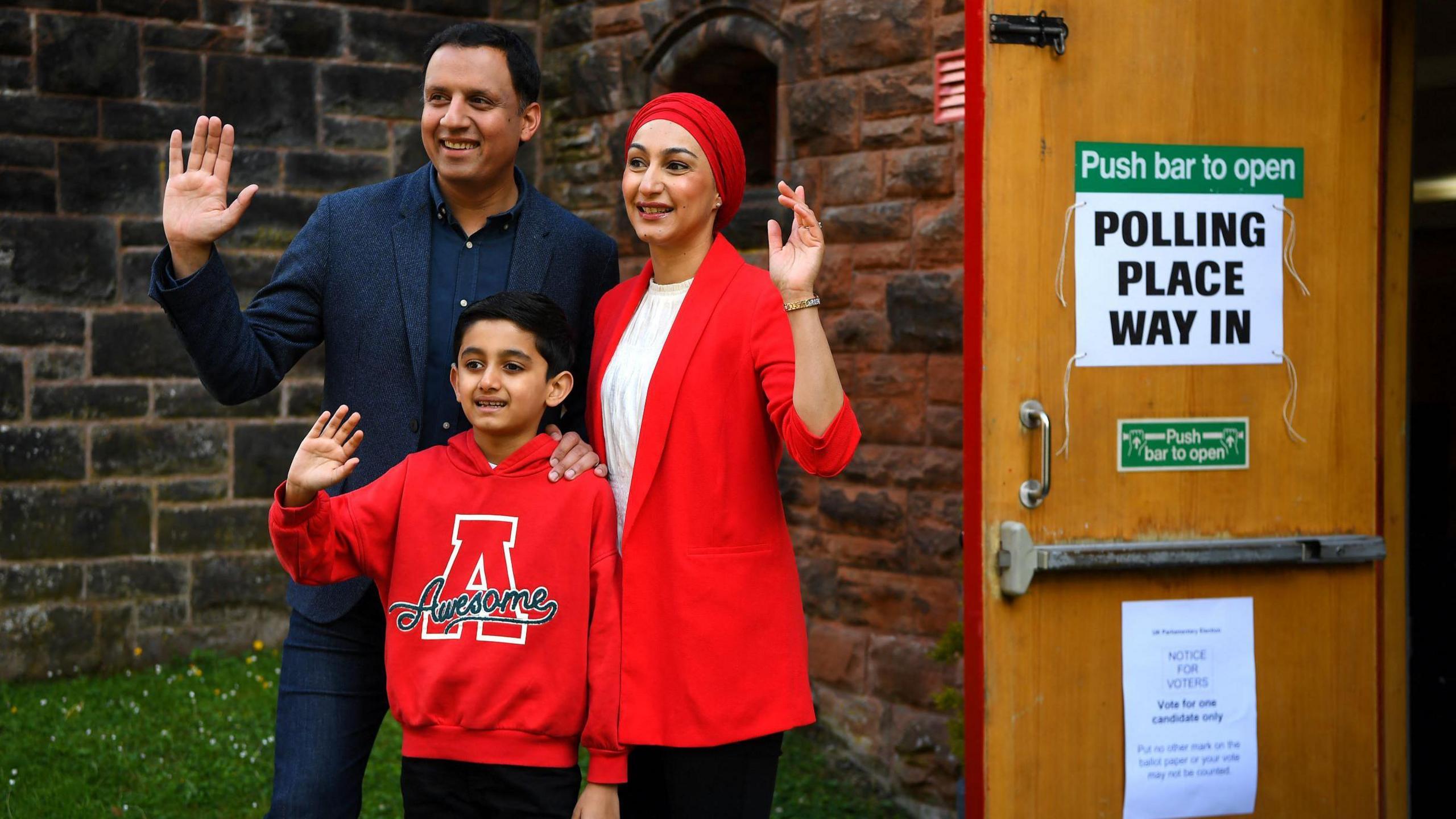 Anas Sarwar waves ahead of casting his vote in the 2024 general election, alongside his family