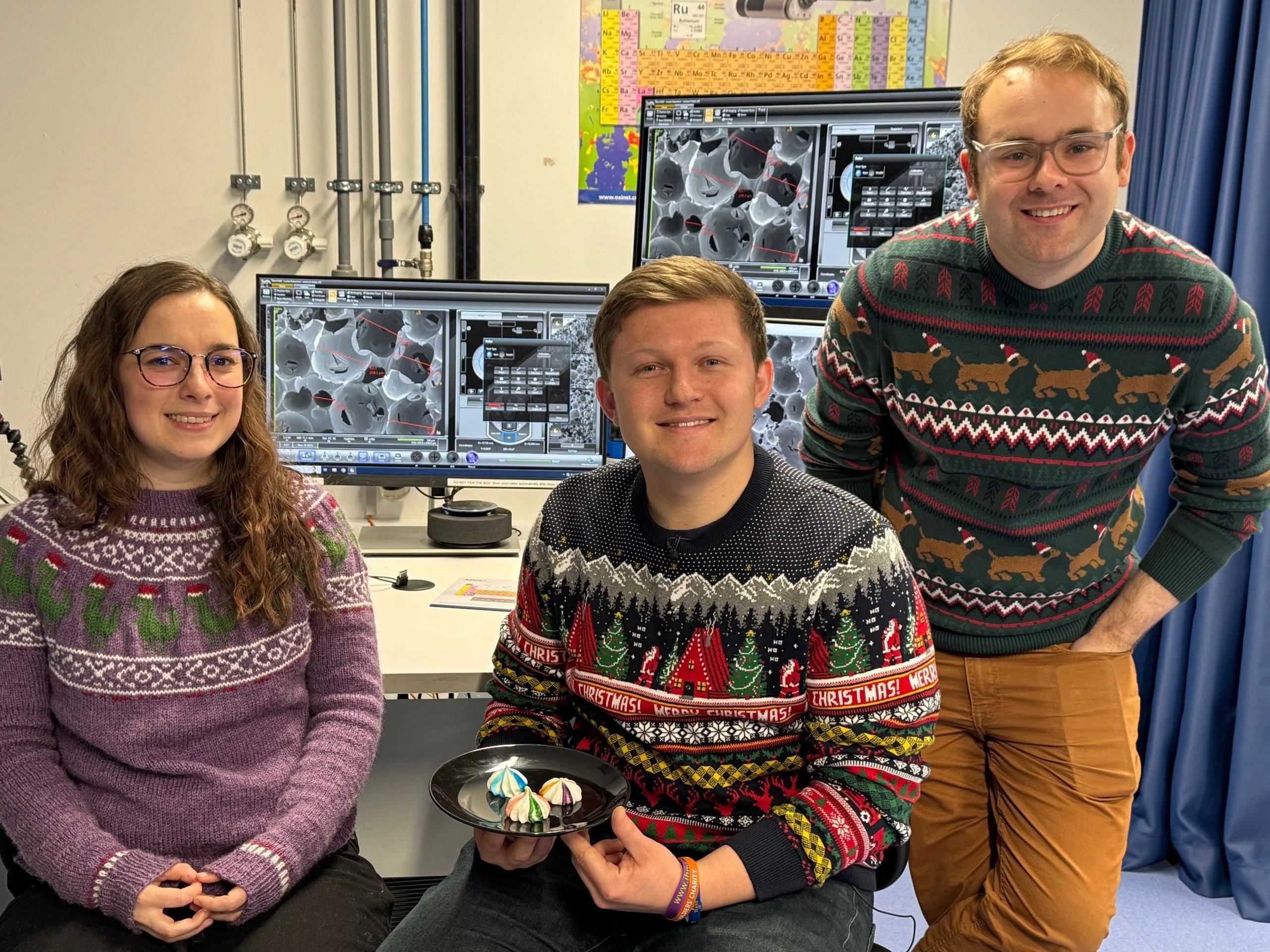 Dr Josh Smalley is holding a plate of meringues which are examined by experts in nanoscience Lorelei Robertson (l) and Luke Norman (r) from the University of Nottingham