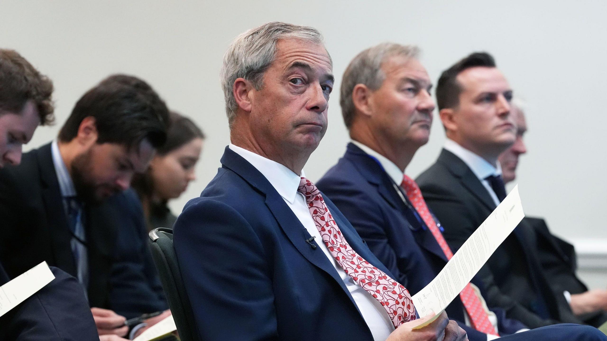 Nigel Farage sat at a press conference