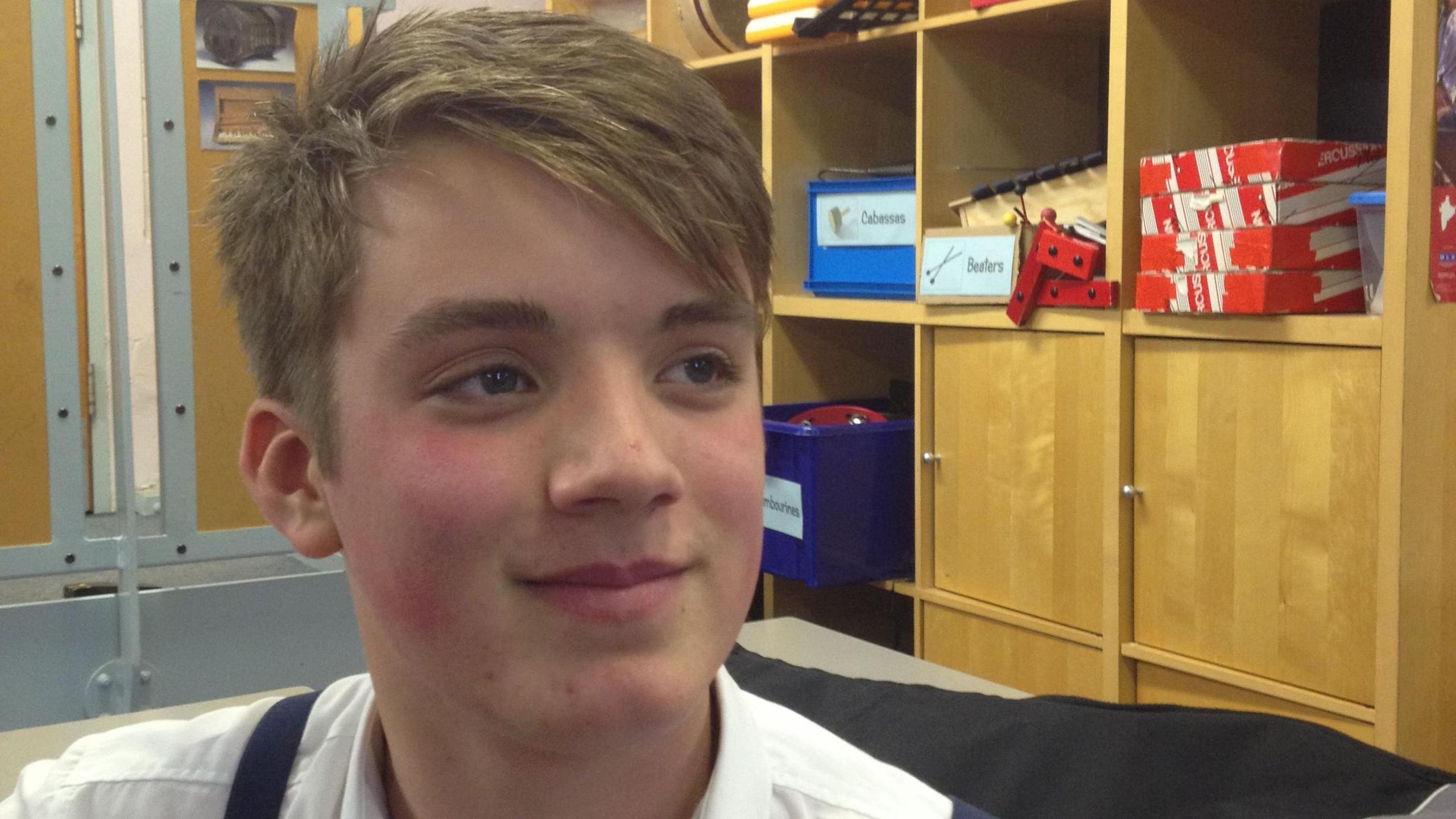 Daniel Spargo-Mabbs smiling with short blonde hair in a white shirt in a classroom. 