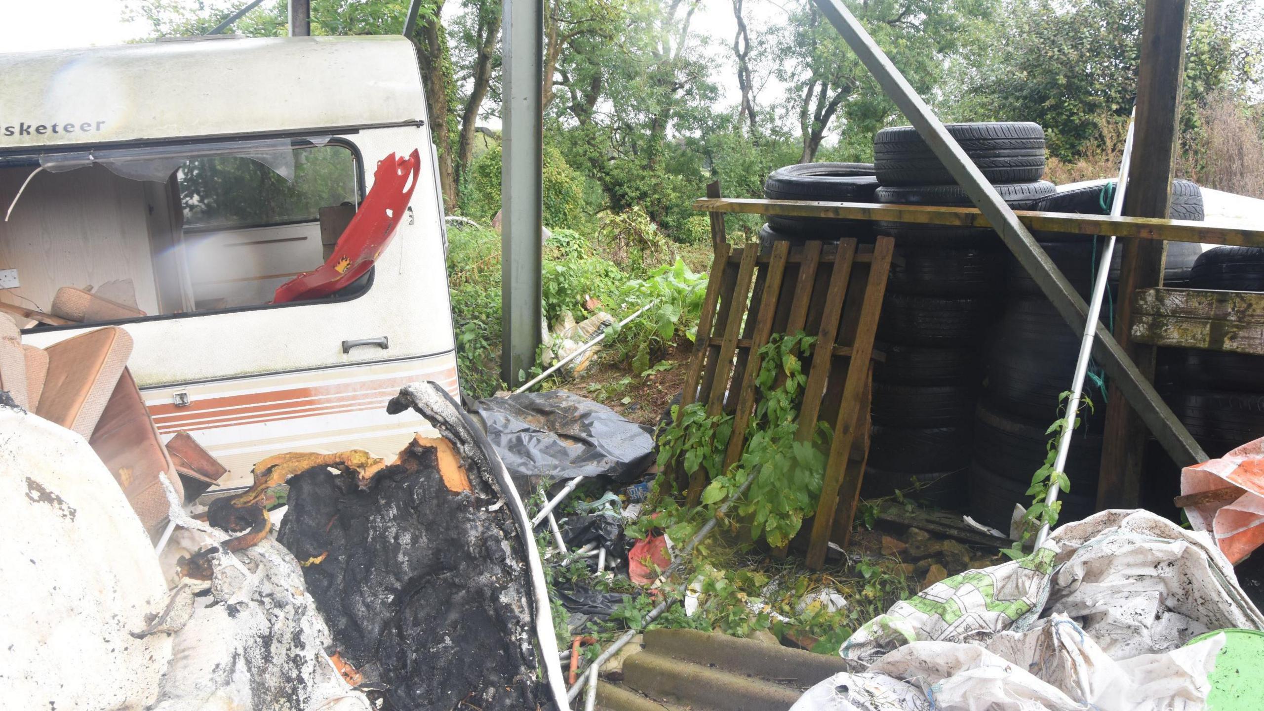 The site where Michael Wheeler's remains were found, with an old-fashioned white caravan on the left and various bits of wood and plastic packaging strewn around