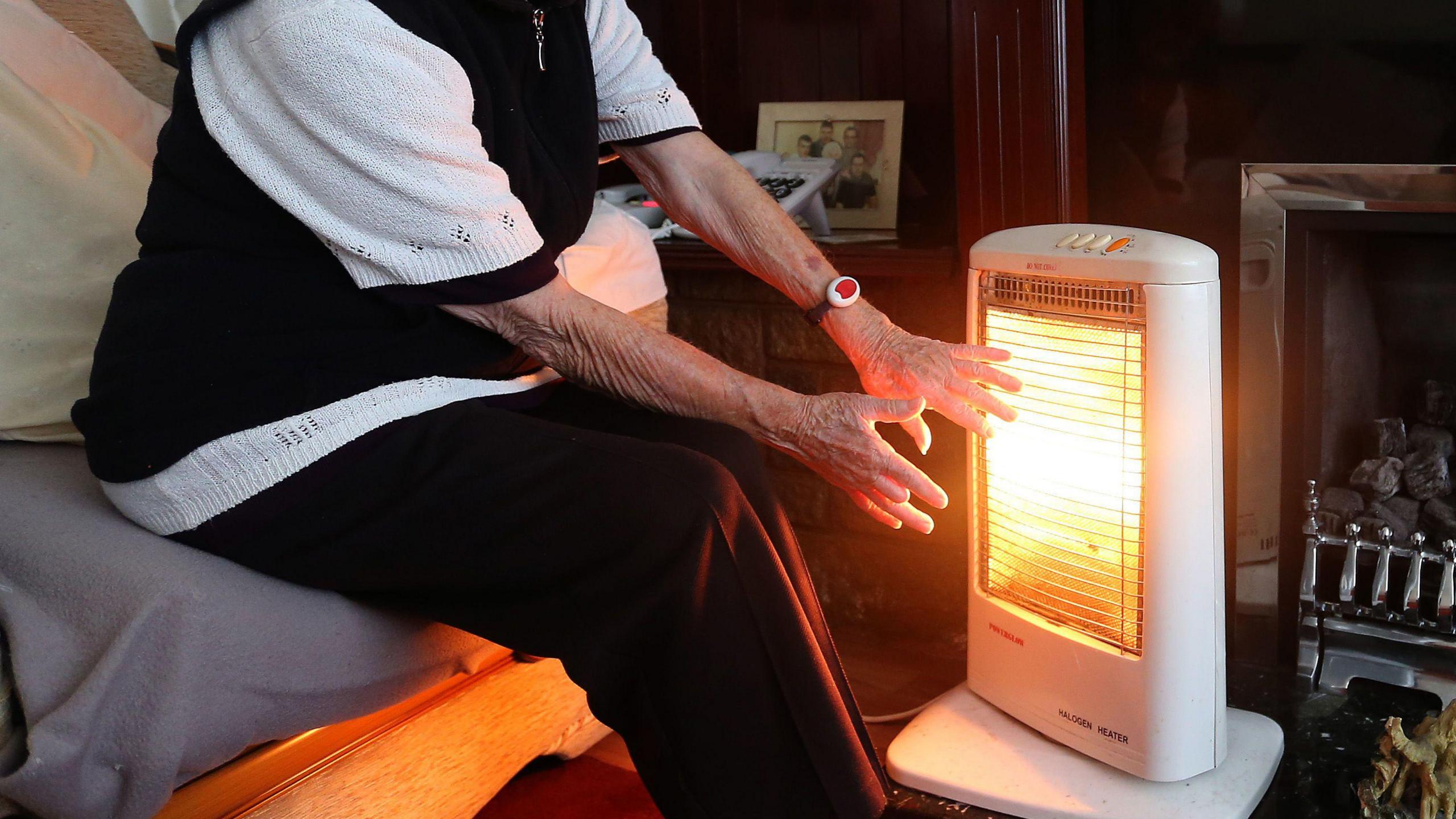 Pensioner warming hands on radiator