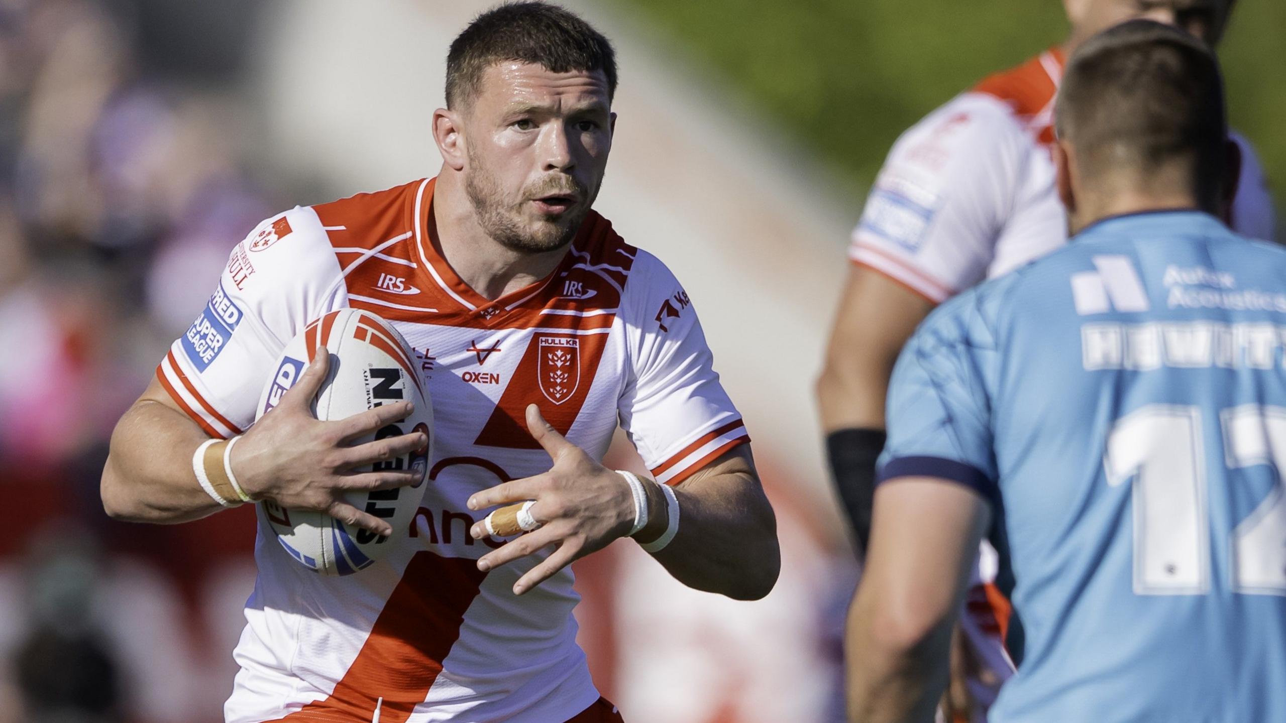James Batchelor carries the ball and runs at an opponent
