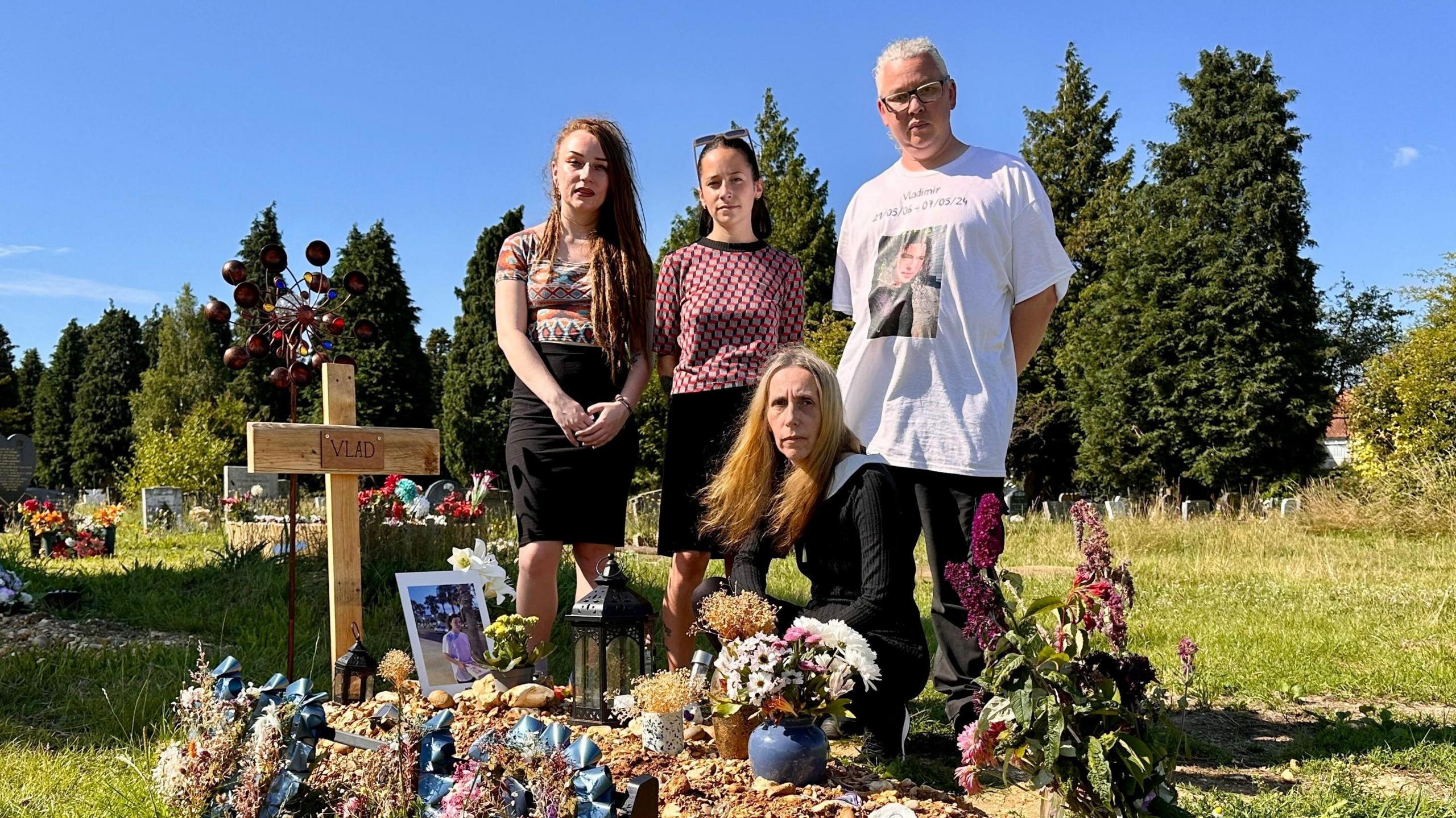 Vlad's family, Mia, Masha, Anna & Graham at his graveside in Southampton which is covered in tributes and marked by a home made wooden cross with his name on