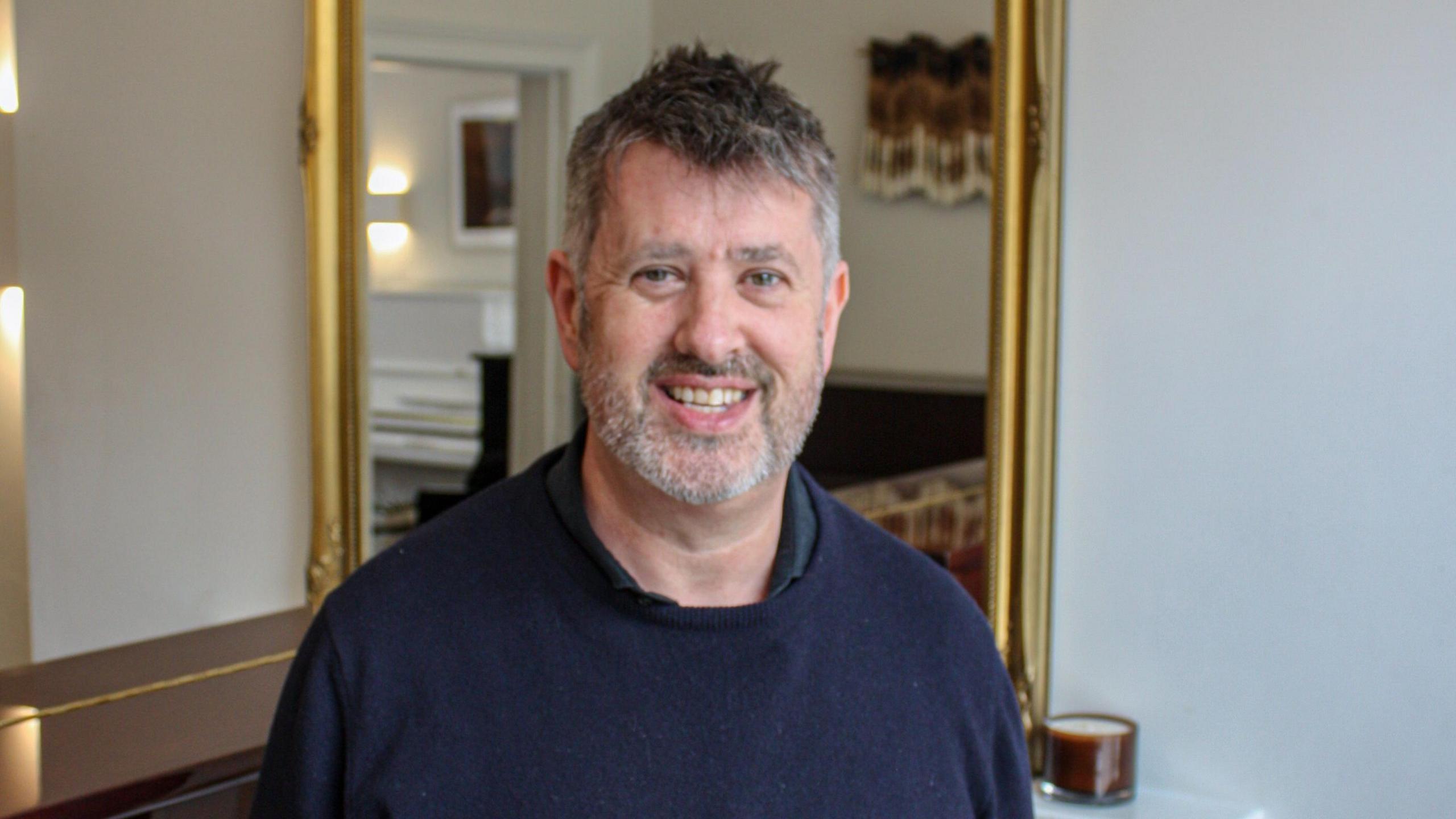 Jon Kelly standing in his shop smiling at the camera