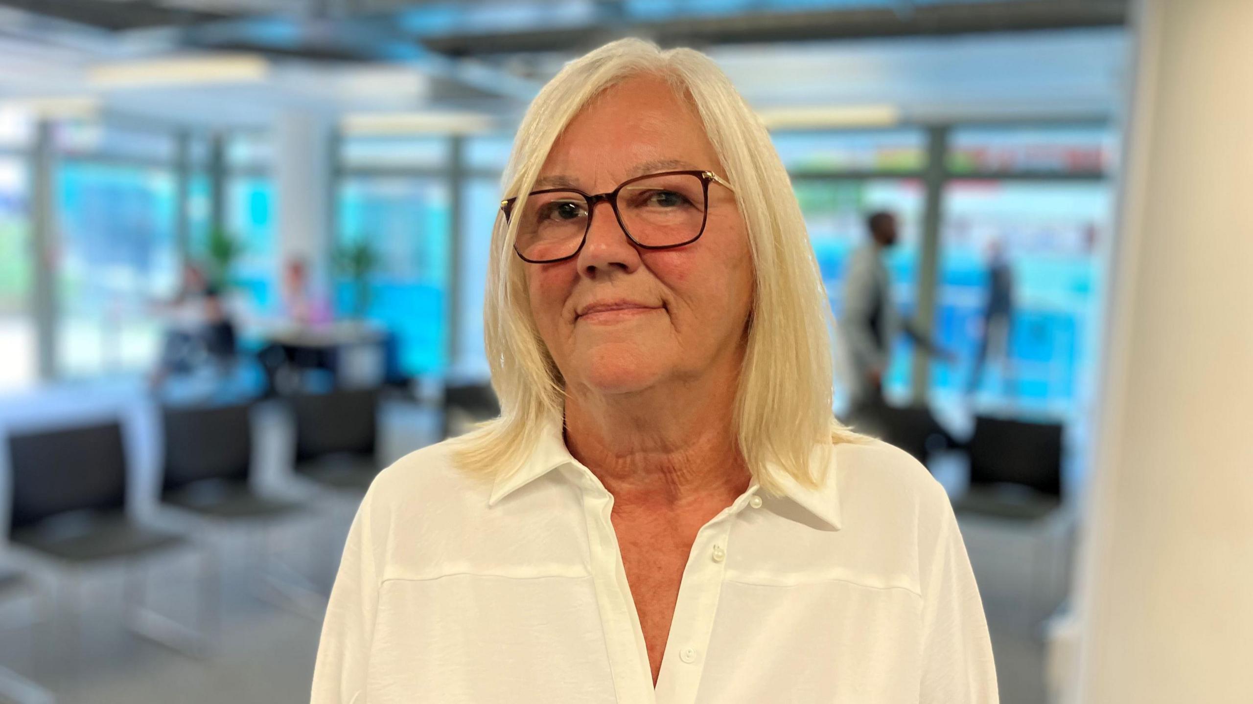 Head and shoulders shot of Zoe Joyner, who is blonde with glasses and wearing a white blouse