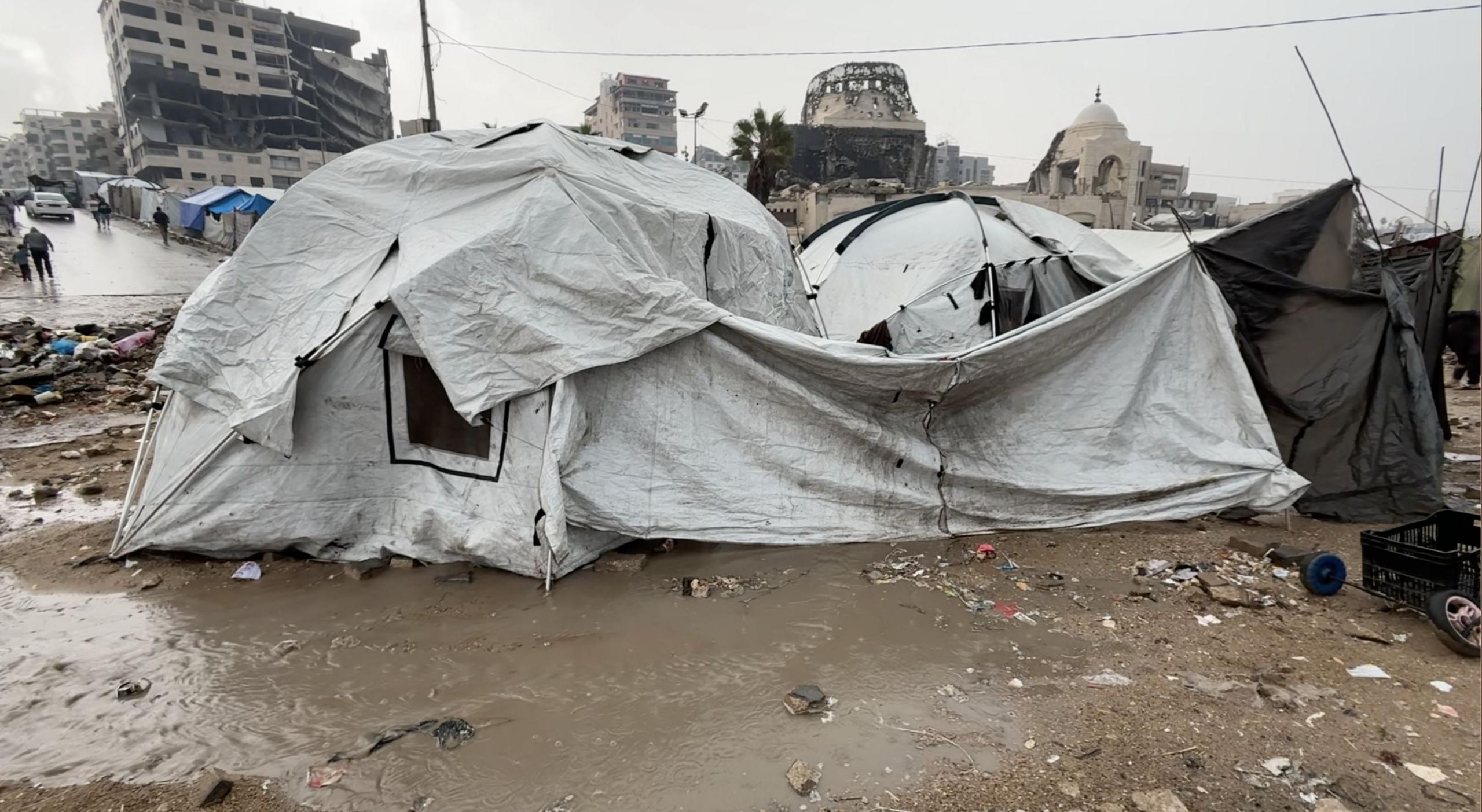 Battered tents sitting on wet and muddy ground