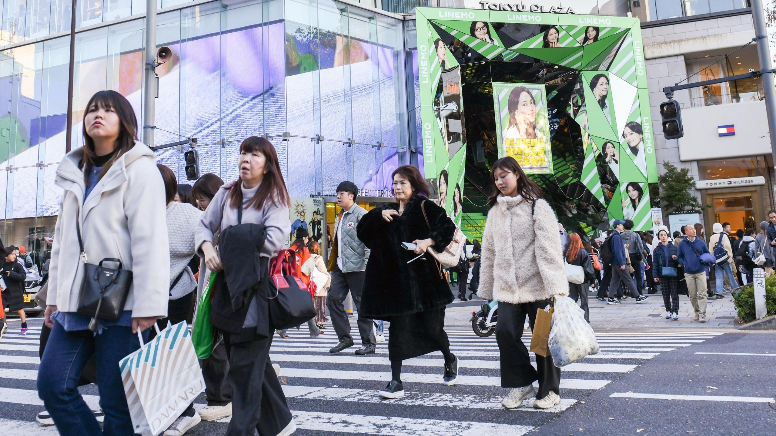 Pedestrians carry shopping bags in the Harajuku district of Tokyo, Japan.