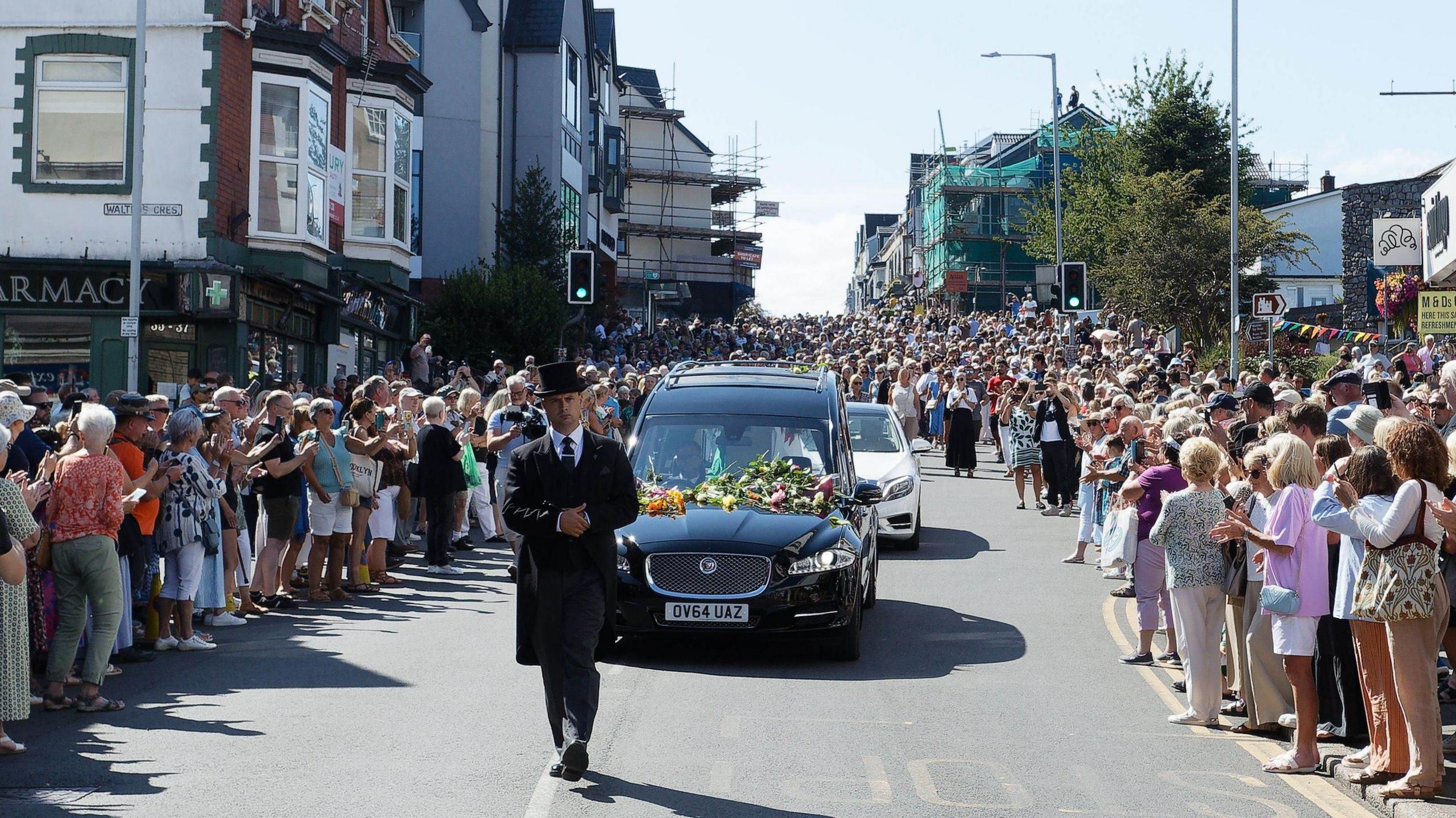 Thousands of fans gathered in the street as Bonnie Tyler's coffin drives down the road in a black funeral car.