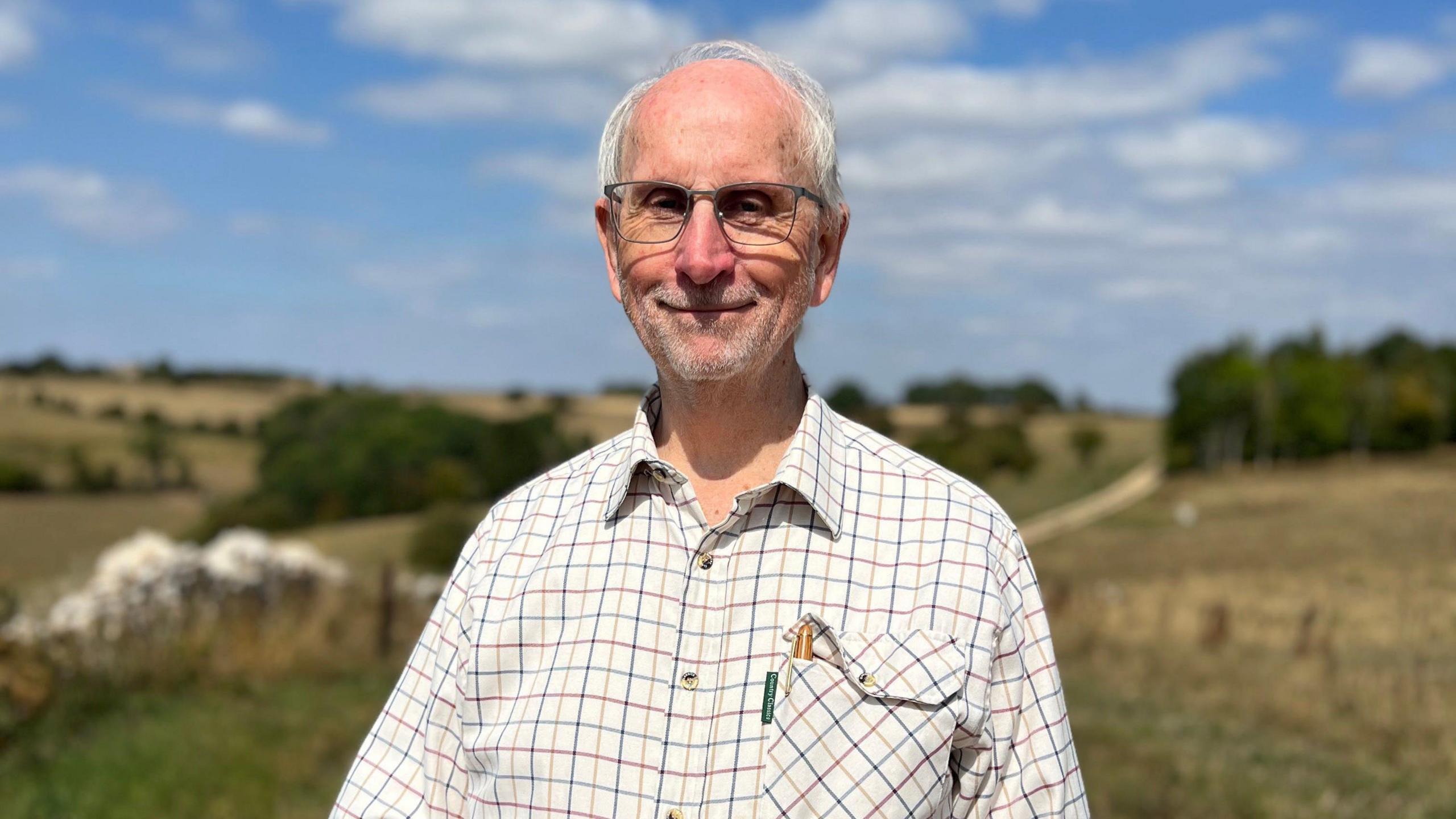 Angus Jenkinson wears a checked shirt and rectangular spectacles