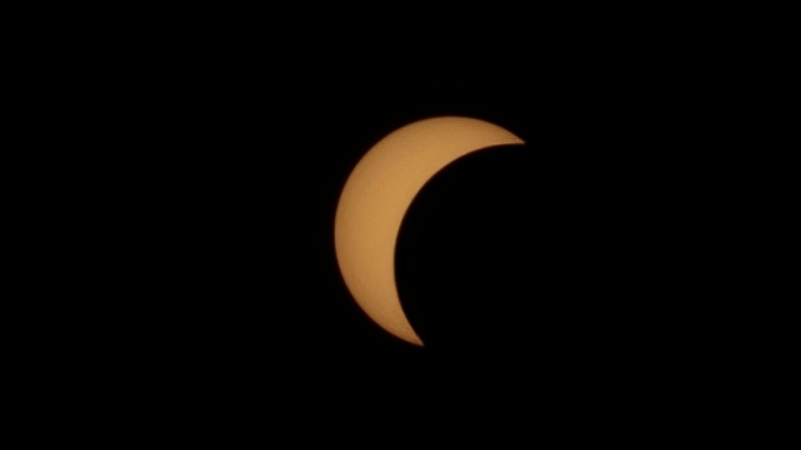 A yellow-coloured semi-circled sun in the otherwise black sky.