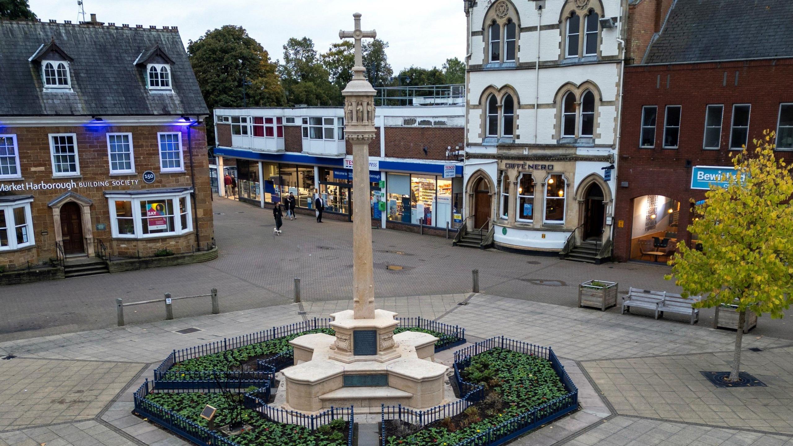 War memorial looking clean and white set in garden in the centre of the town square surrounded by shops