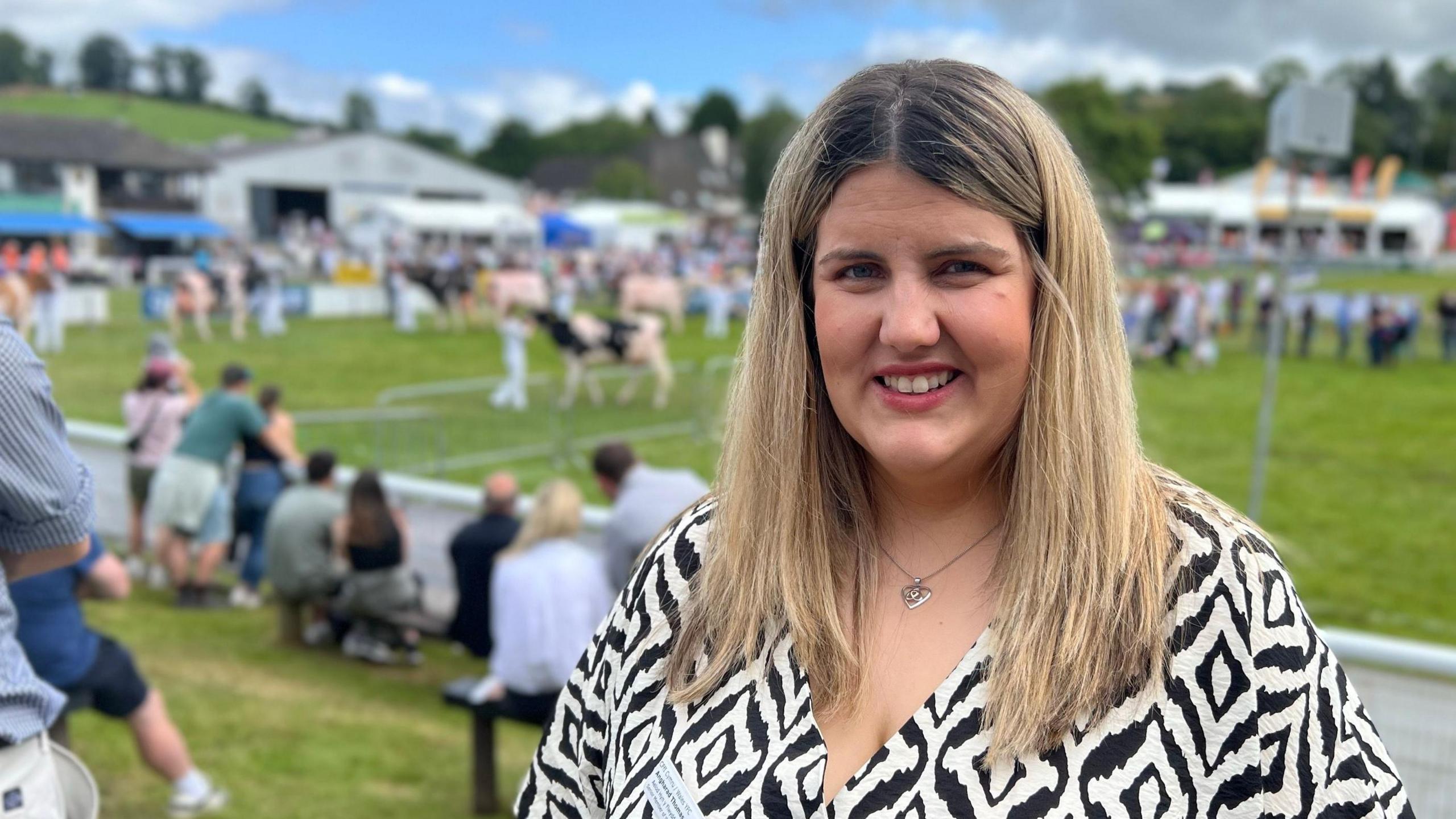 Young woman wearing a black and white print dress standing in front of the cattle showground