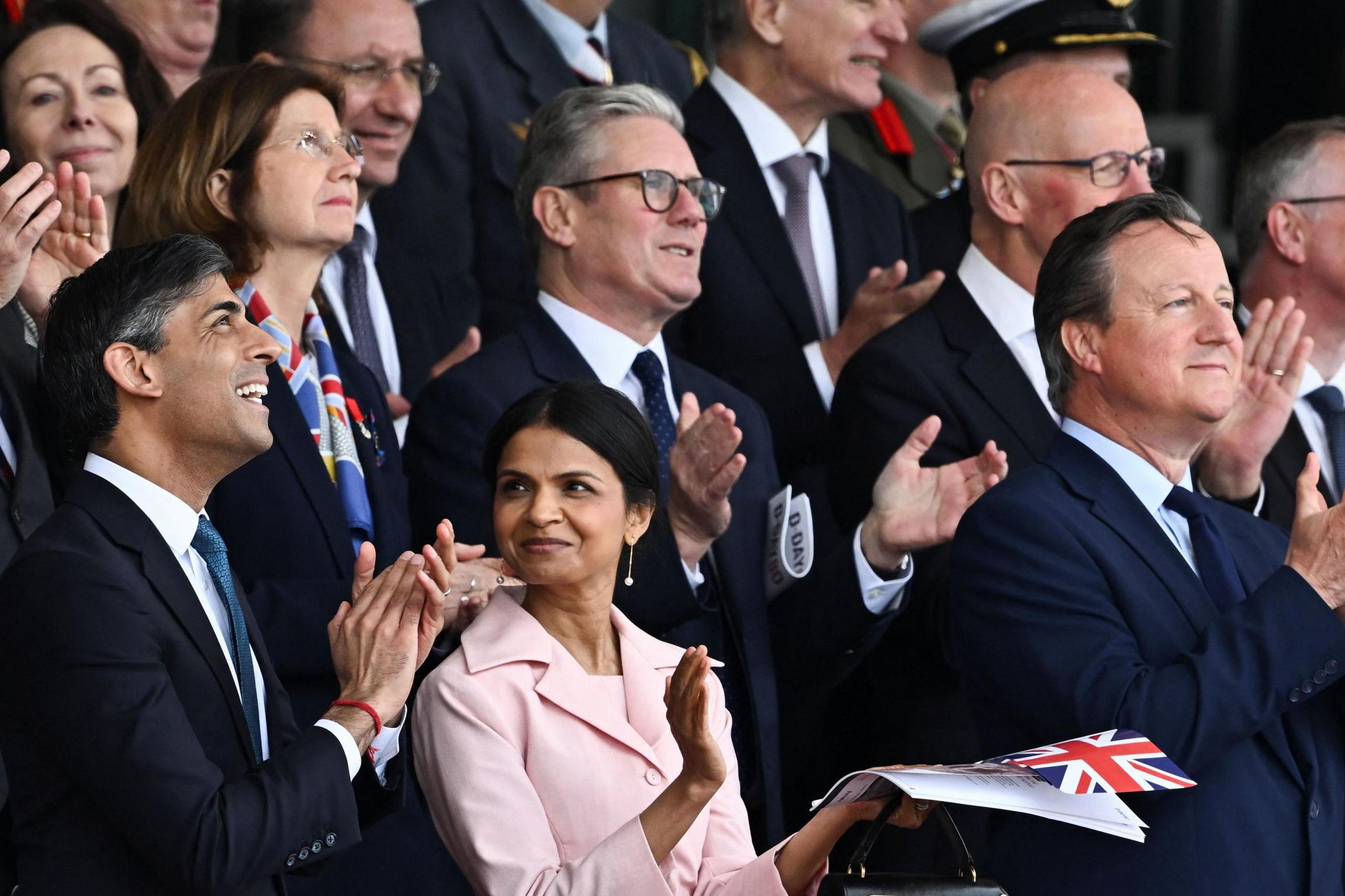 Rishi Sunak and his wife, Akshata Murty, stand in front of Keir Starmer at Normandy D-Day event