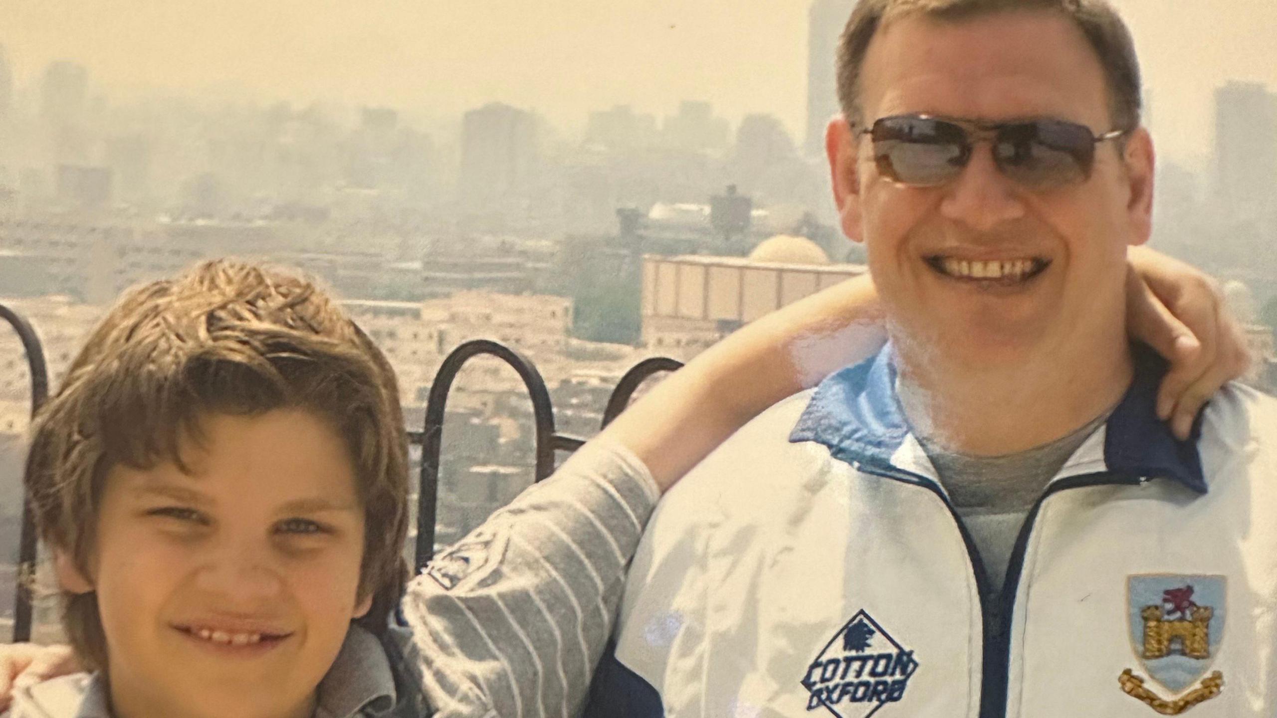 Conor pictured as a young boy with his arm around his father. He is wearing a Swansea rugby club tracksuit top.